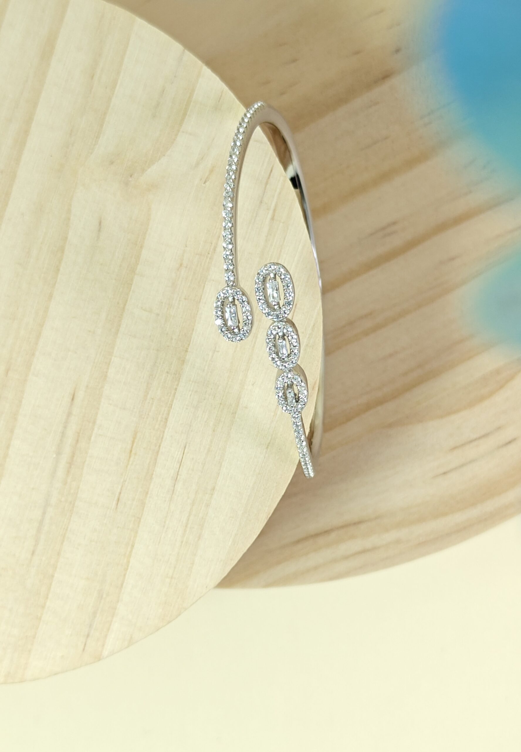 Silver earring with dangling elements on a light wooden surface