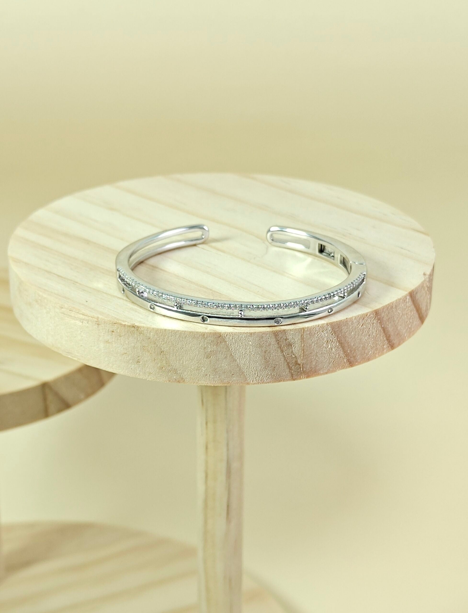 Silver bracelet on a wooden stool with a neutral background