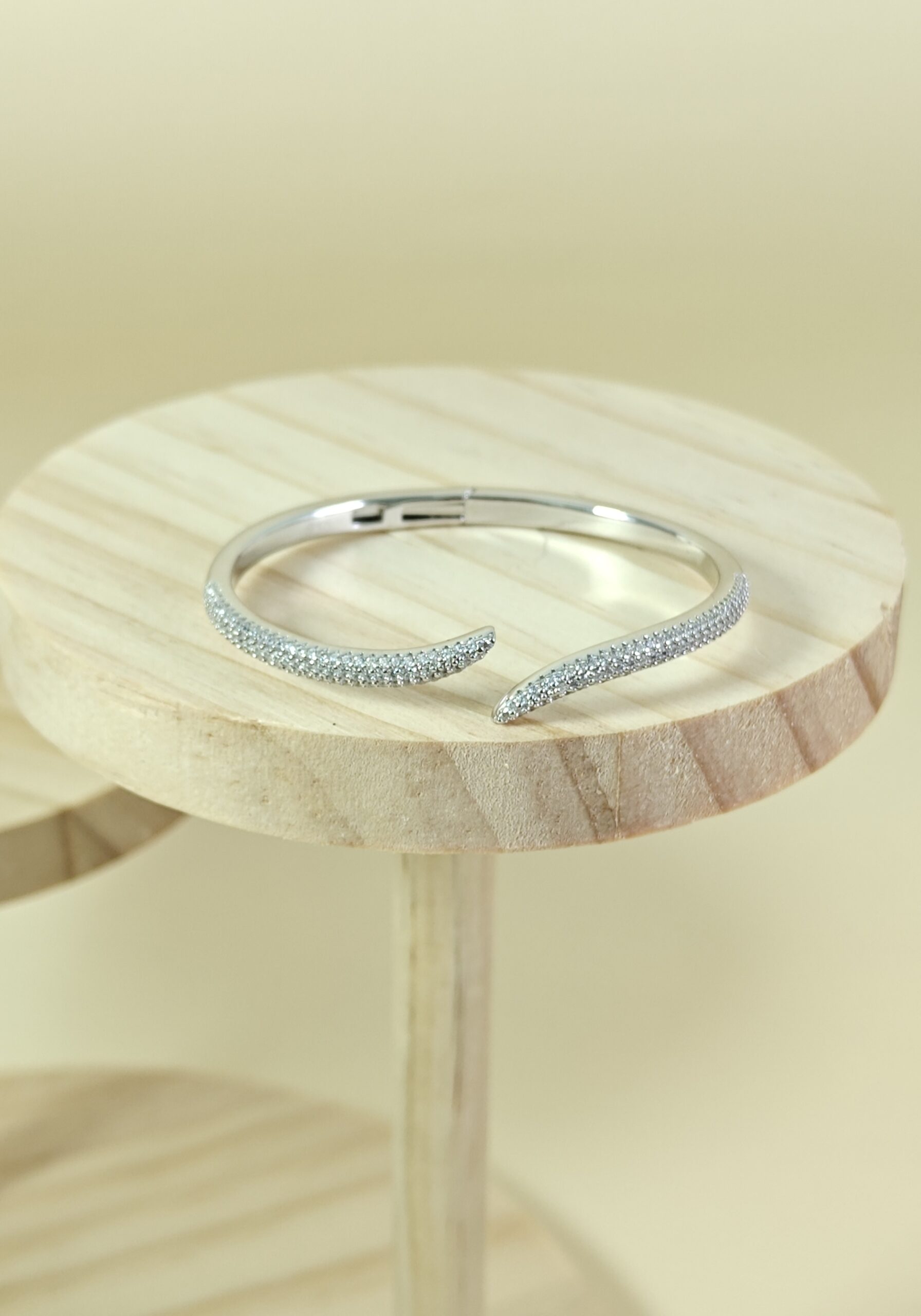 Silver bracelet on a wooden stand with a light background