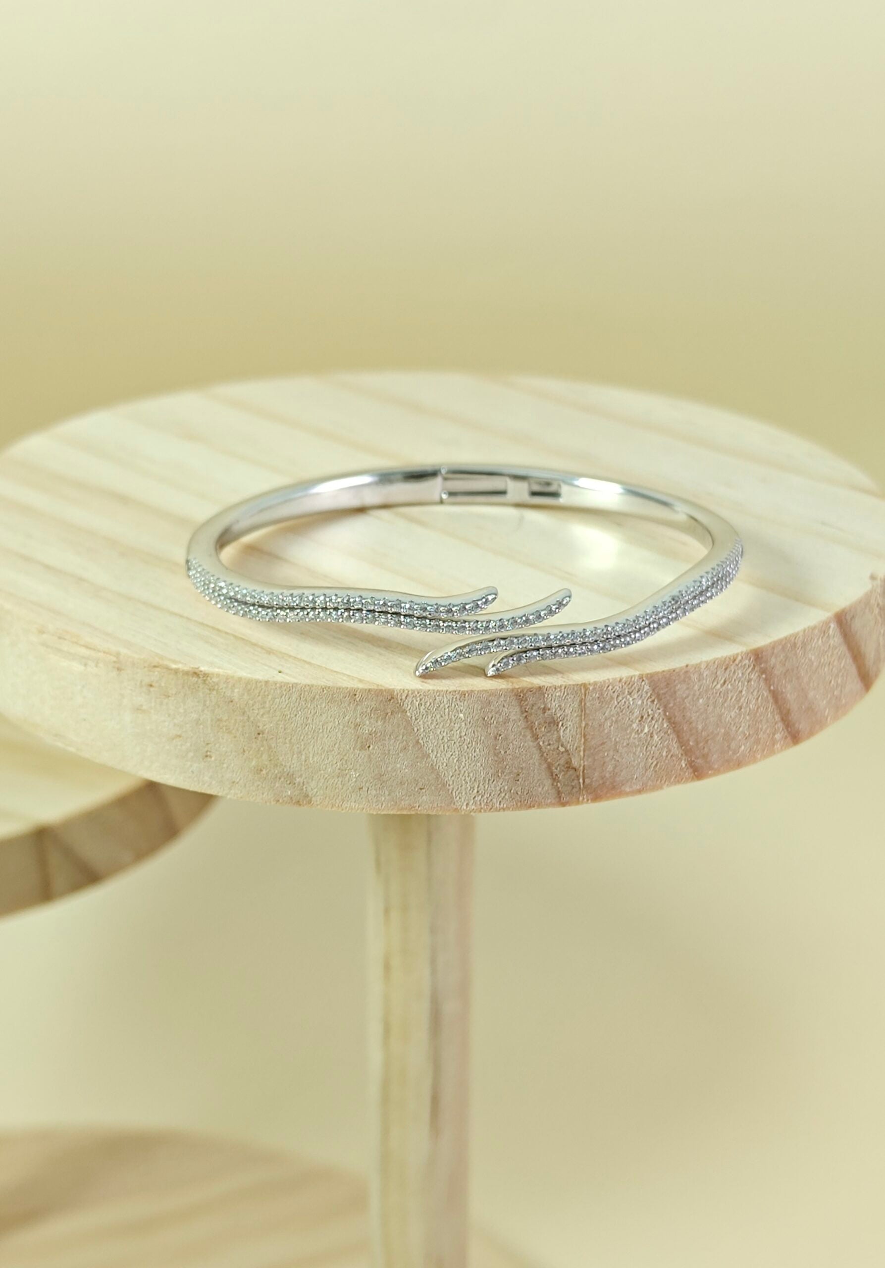 Silver ring on a wooden stand with a beige background