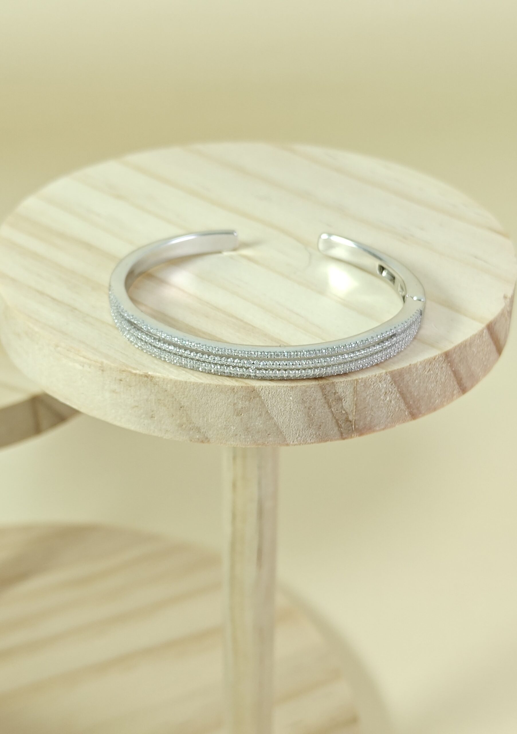 Silver bracelet on a wooden stool with a neutral background