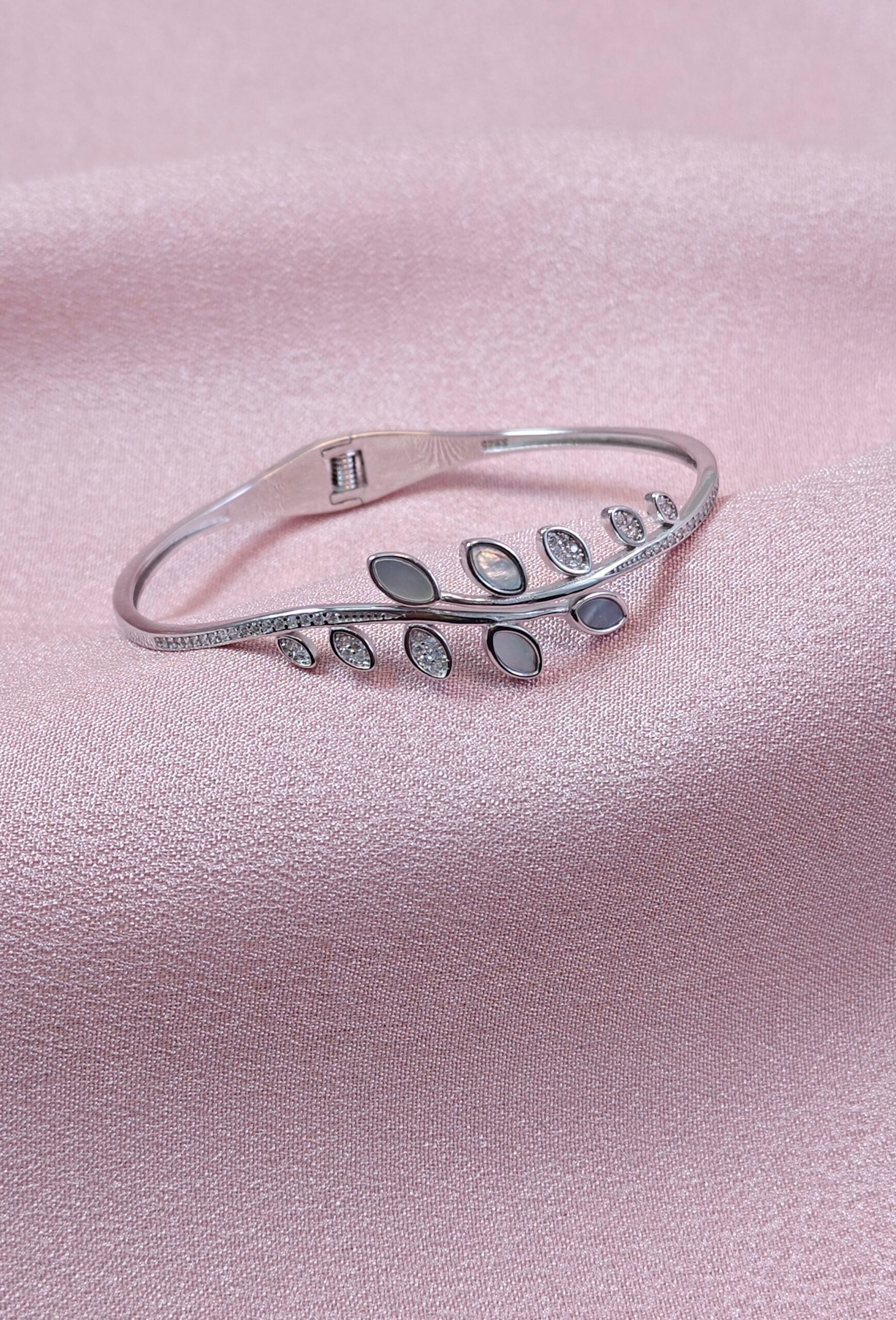 Silver bracelet with leaf design on a pink satin background