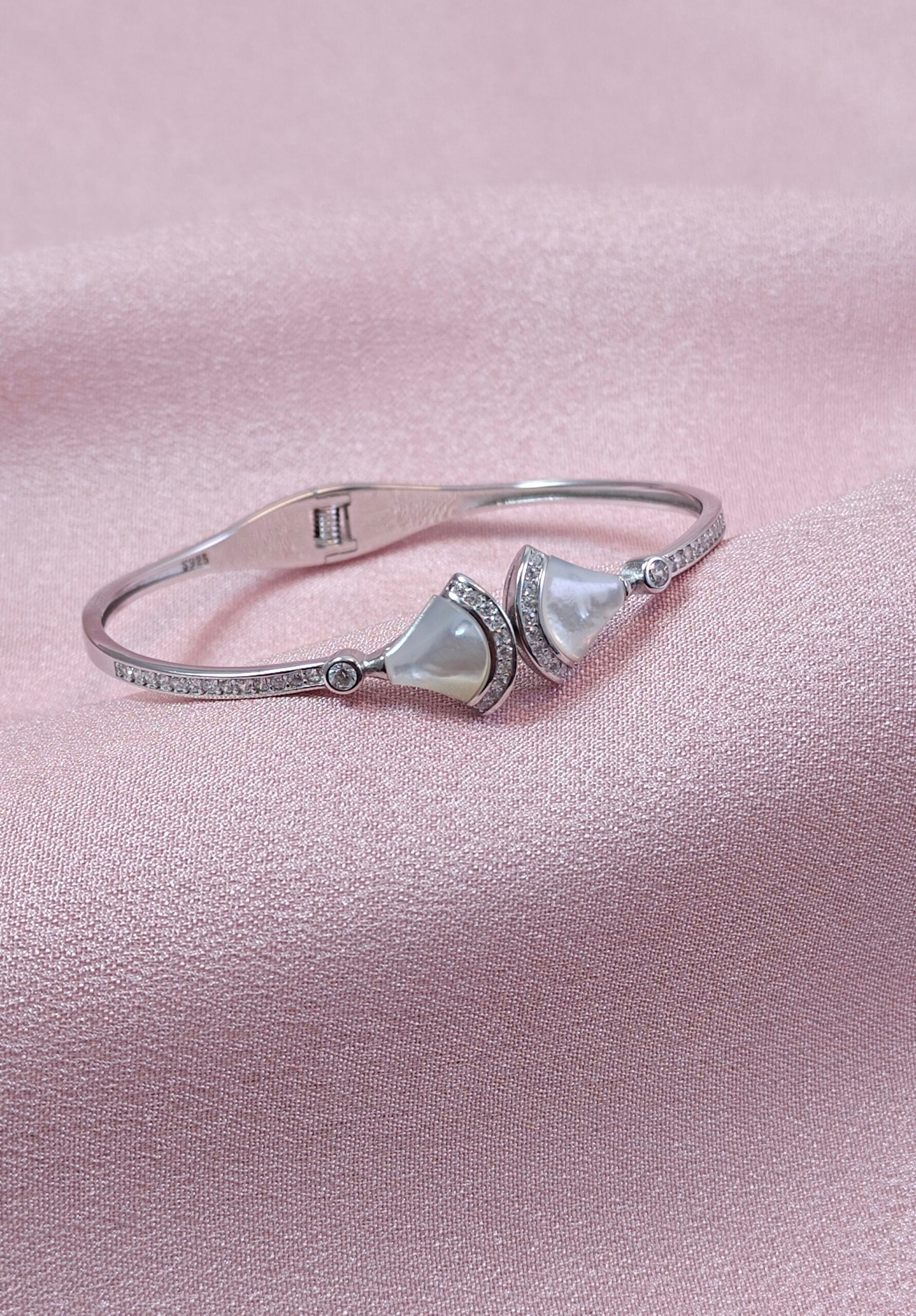 Silver bracelet with pearl-like stones on a pink background