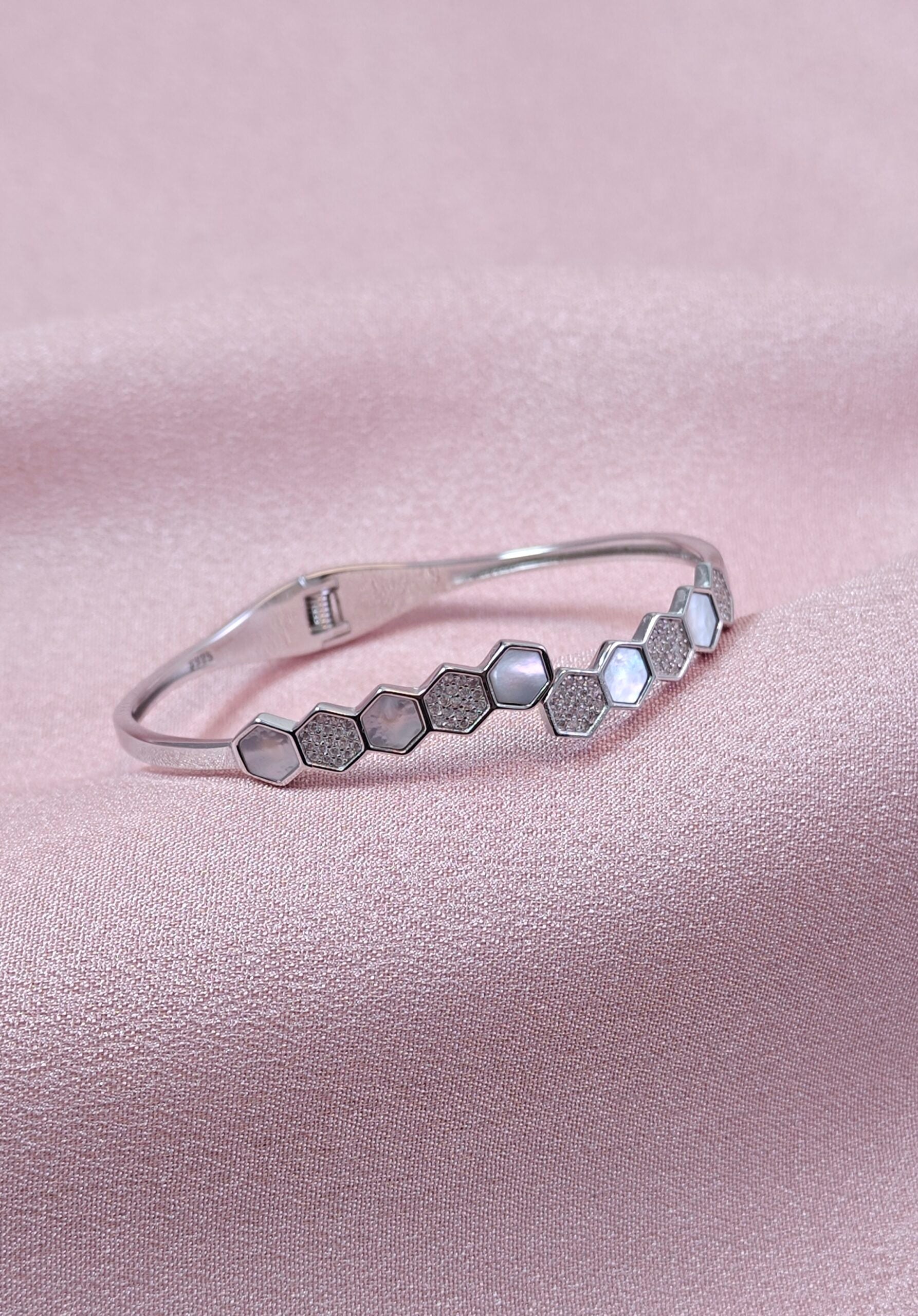 Silver bracelet with hexagonal pattern on a pink satin background