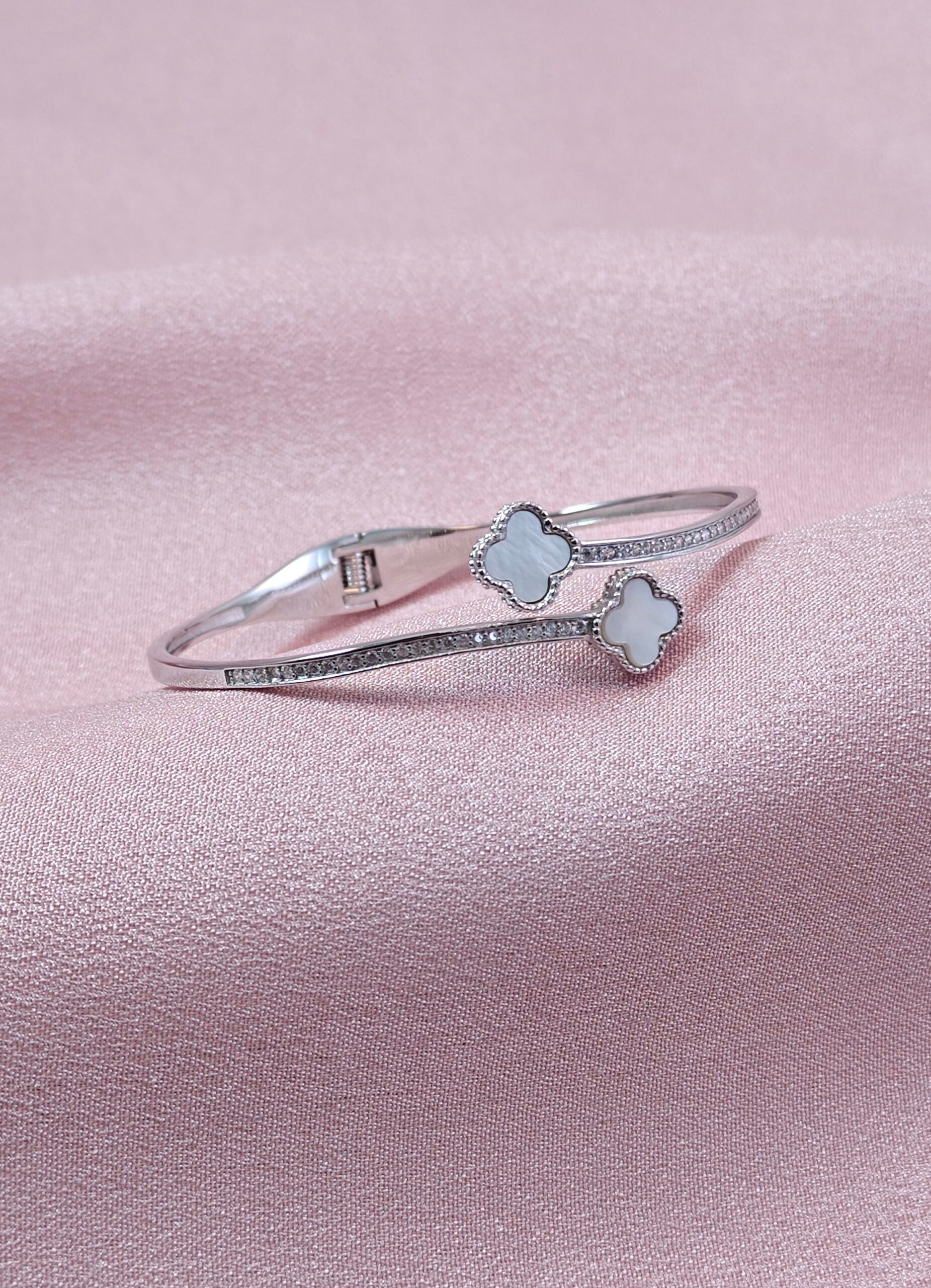 Silver bracelet with floral designs on a pink satin background