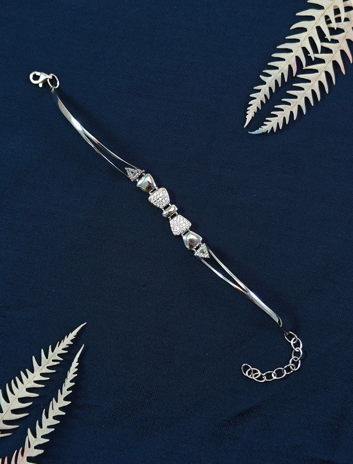 Silver bracelet with beads on a dark blue background with fern leaves