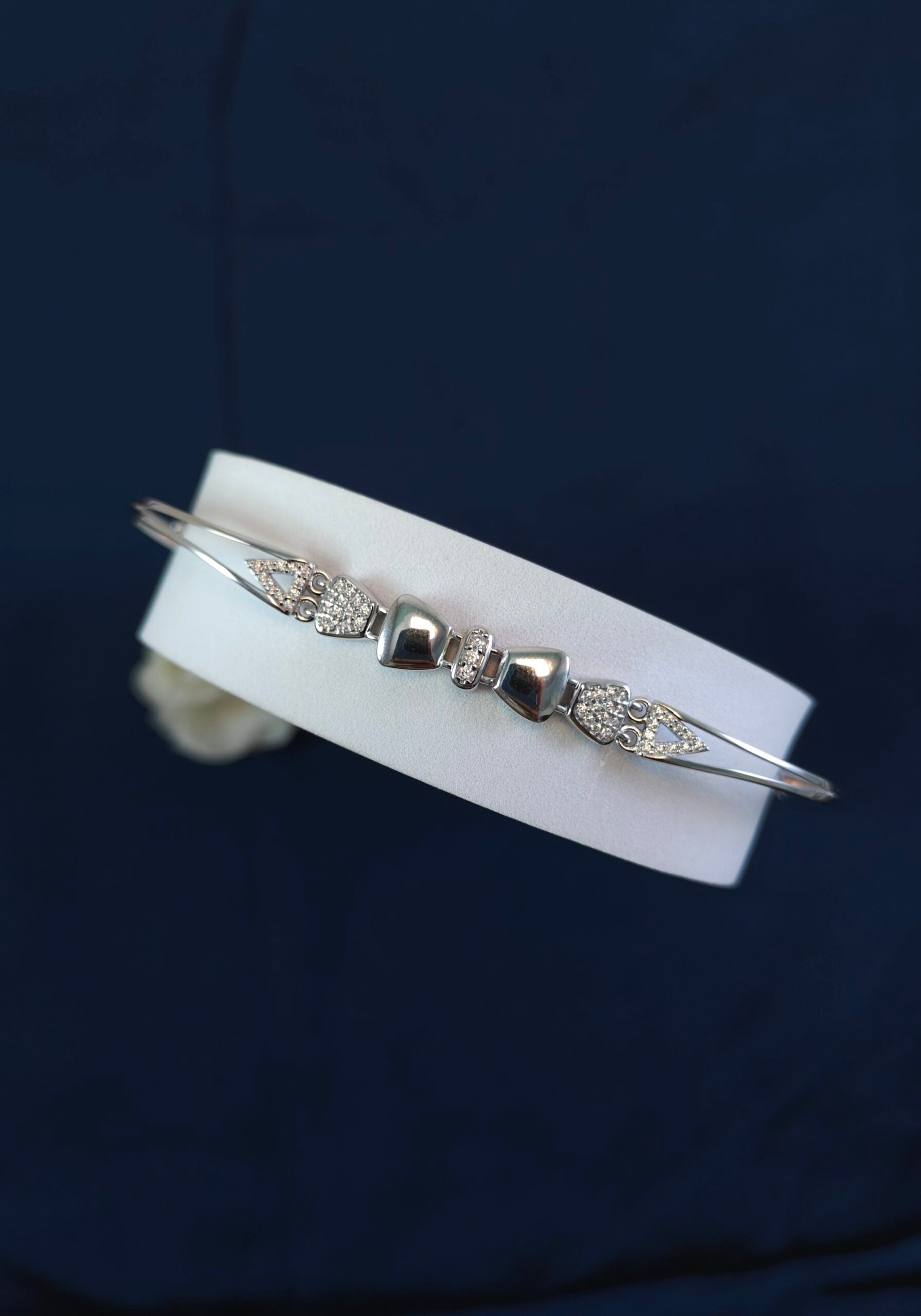 Silver bracelet with diamond accents on a white card against a dark background