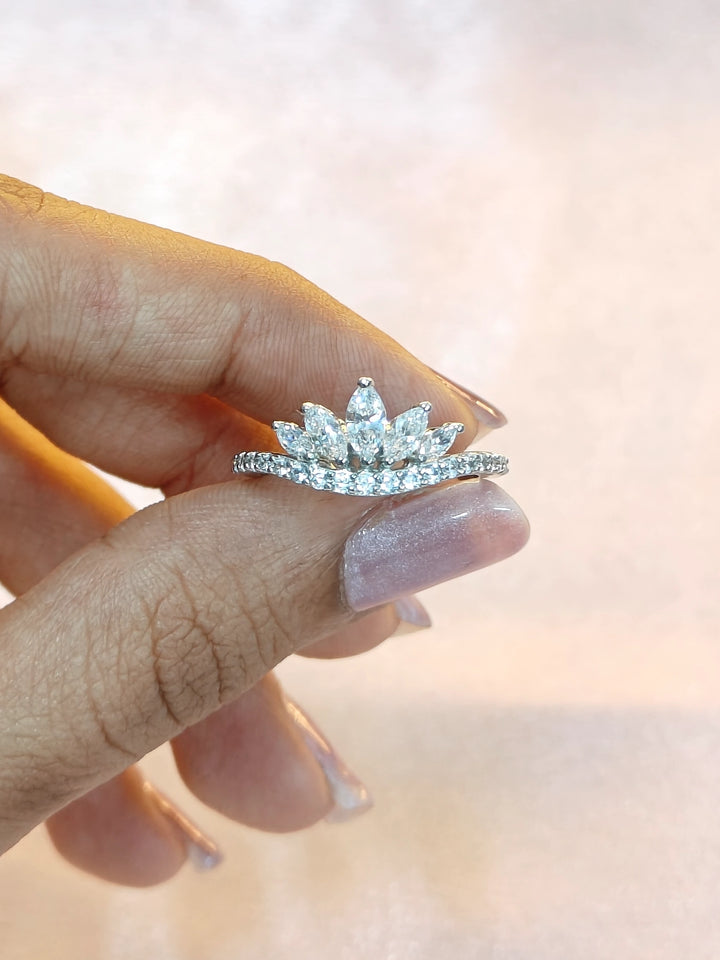 Silver ring with a diamond tiara design held by a hand against a blurred background