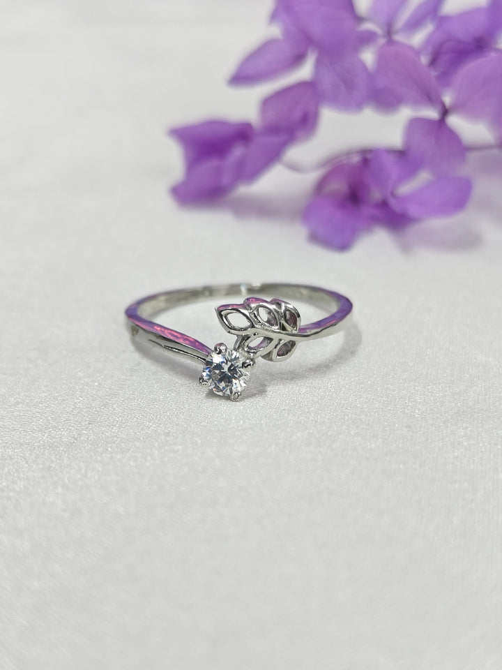 Silver ring with a purple accent on a white background with purple flowers.