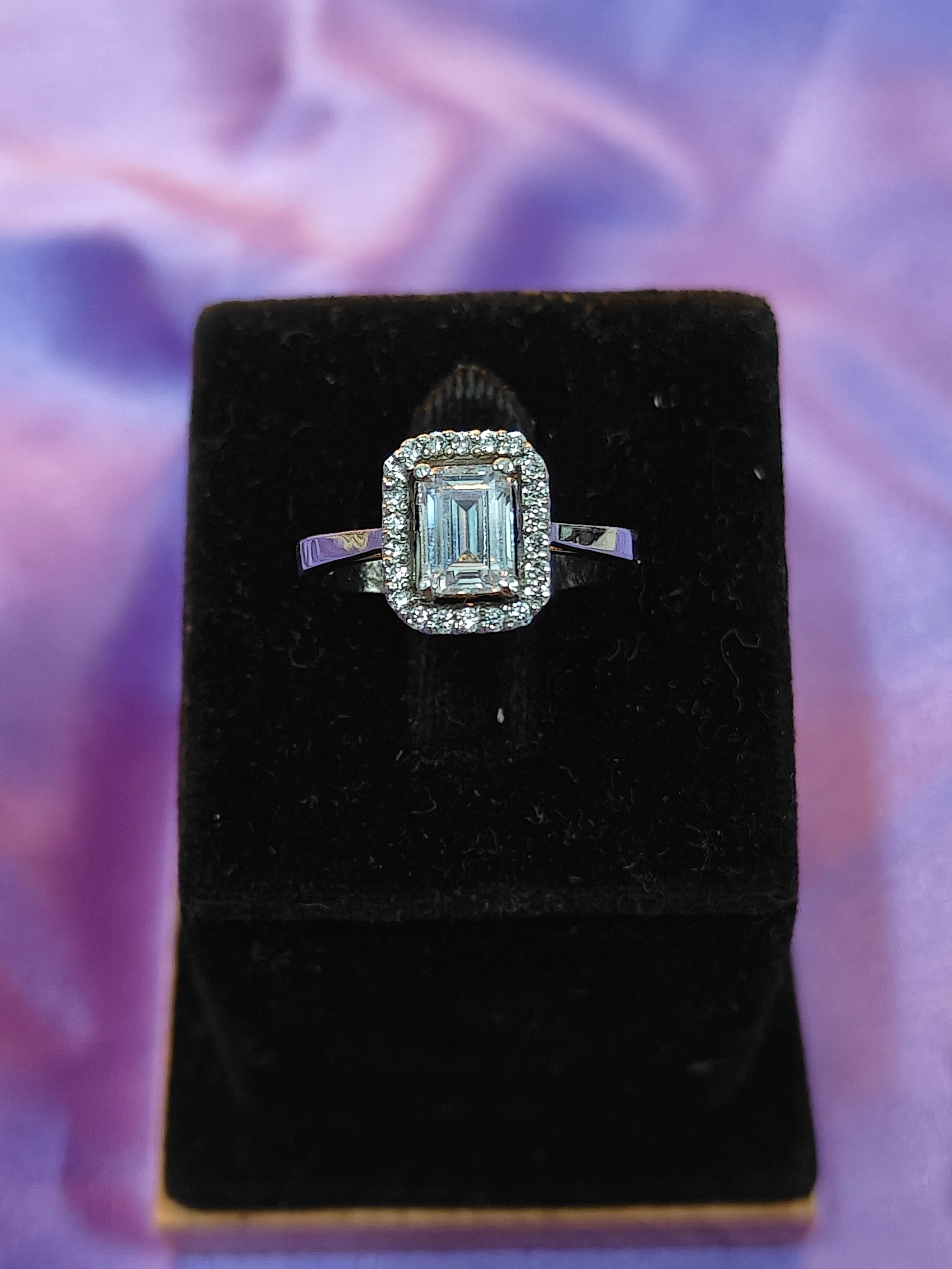Diamond ring on a black velvet cushion with a purple abstract background