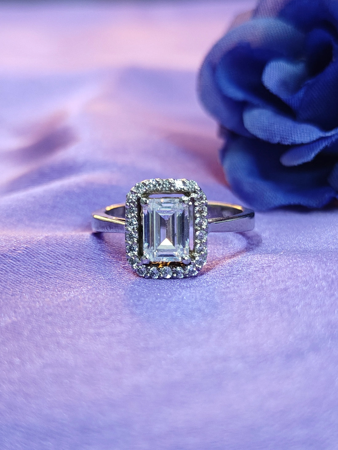 Diamond ring on a purple fabric background with a blue flower