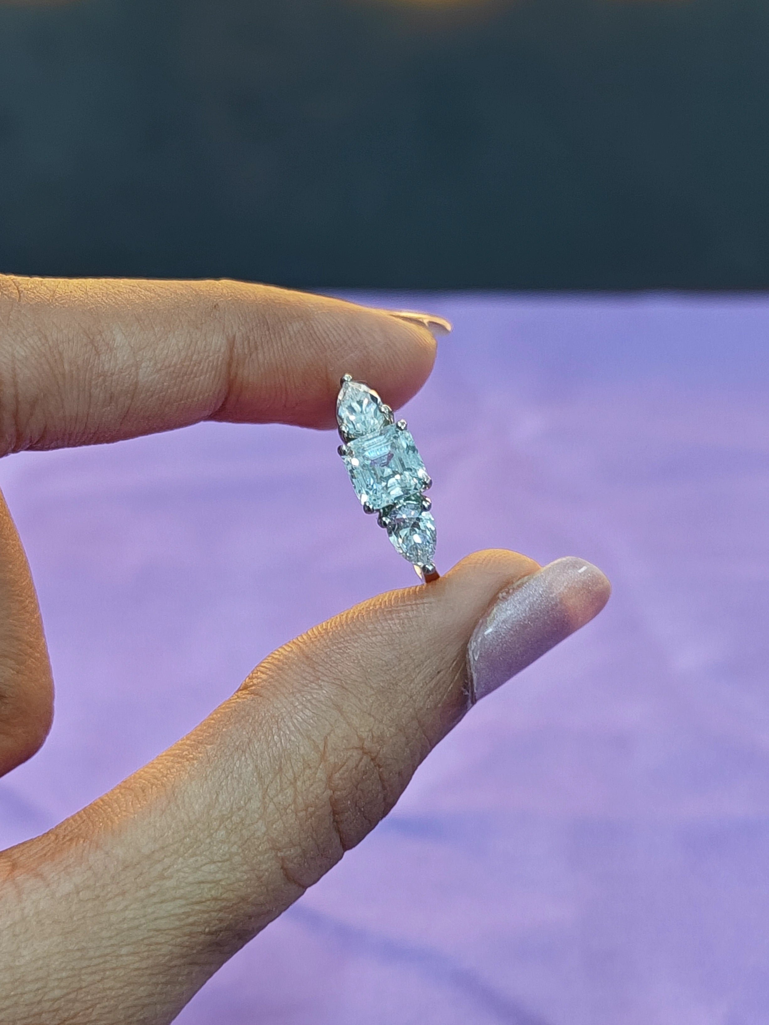 Diamond ring held between fingers with a blurred background