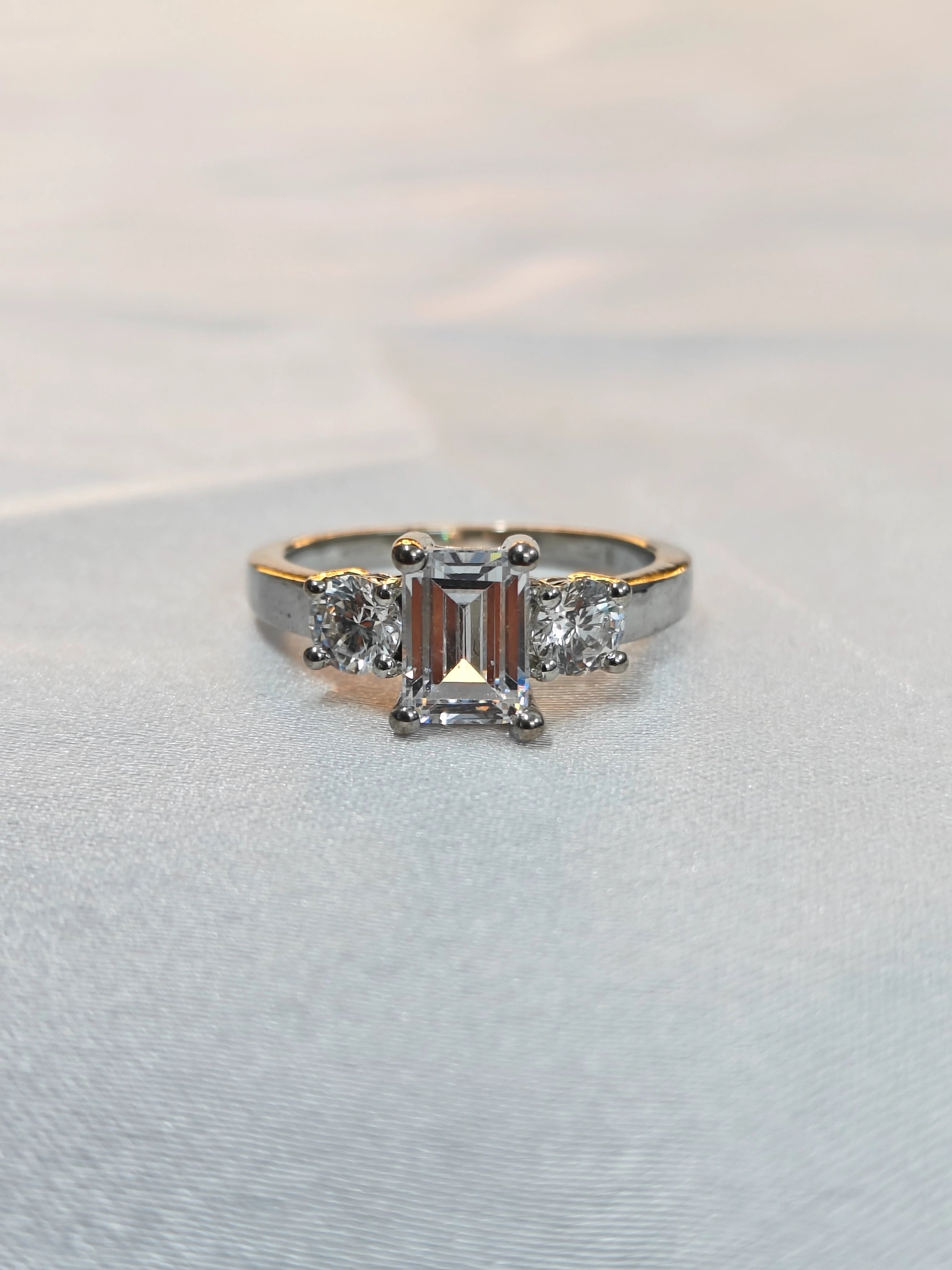 Gold ring with three diamonds on a light gray background