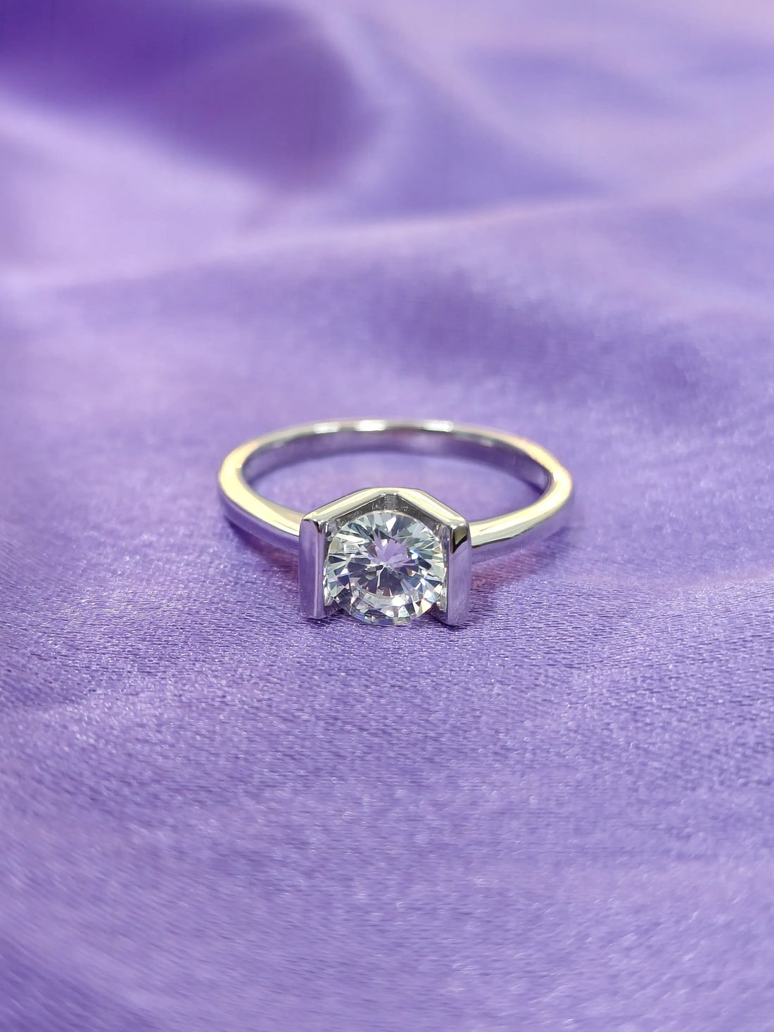Gold ring with a diamond on a purple fabric background