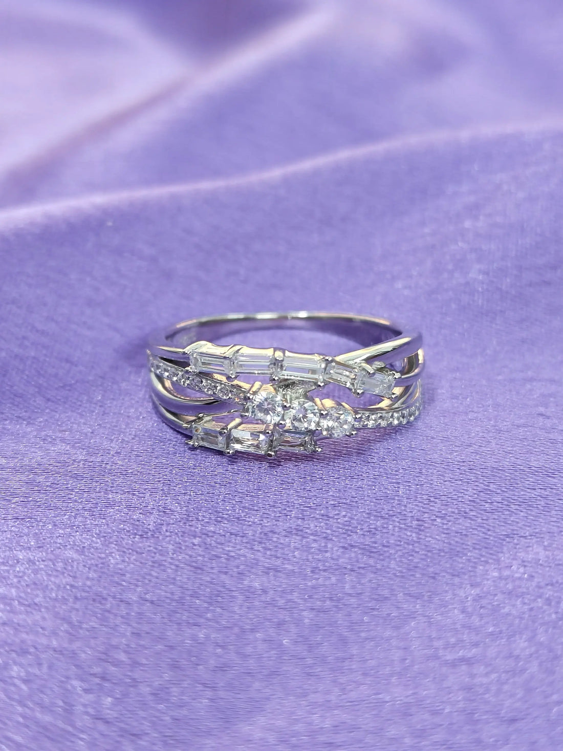 Silver ring with gemstones on a purple fabric background