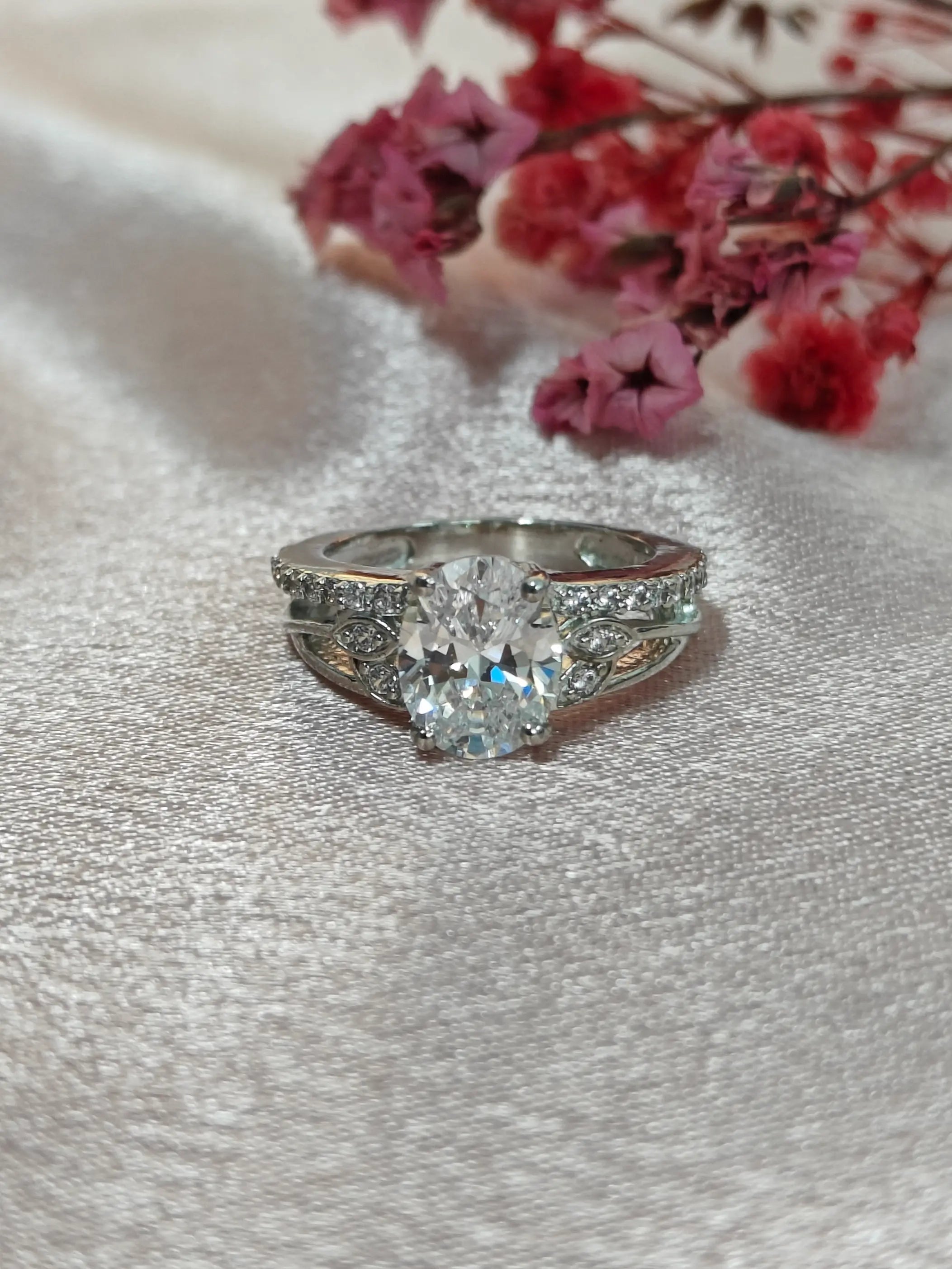Diamond ring on a textured surface with pink flowers in the background