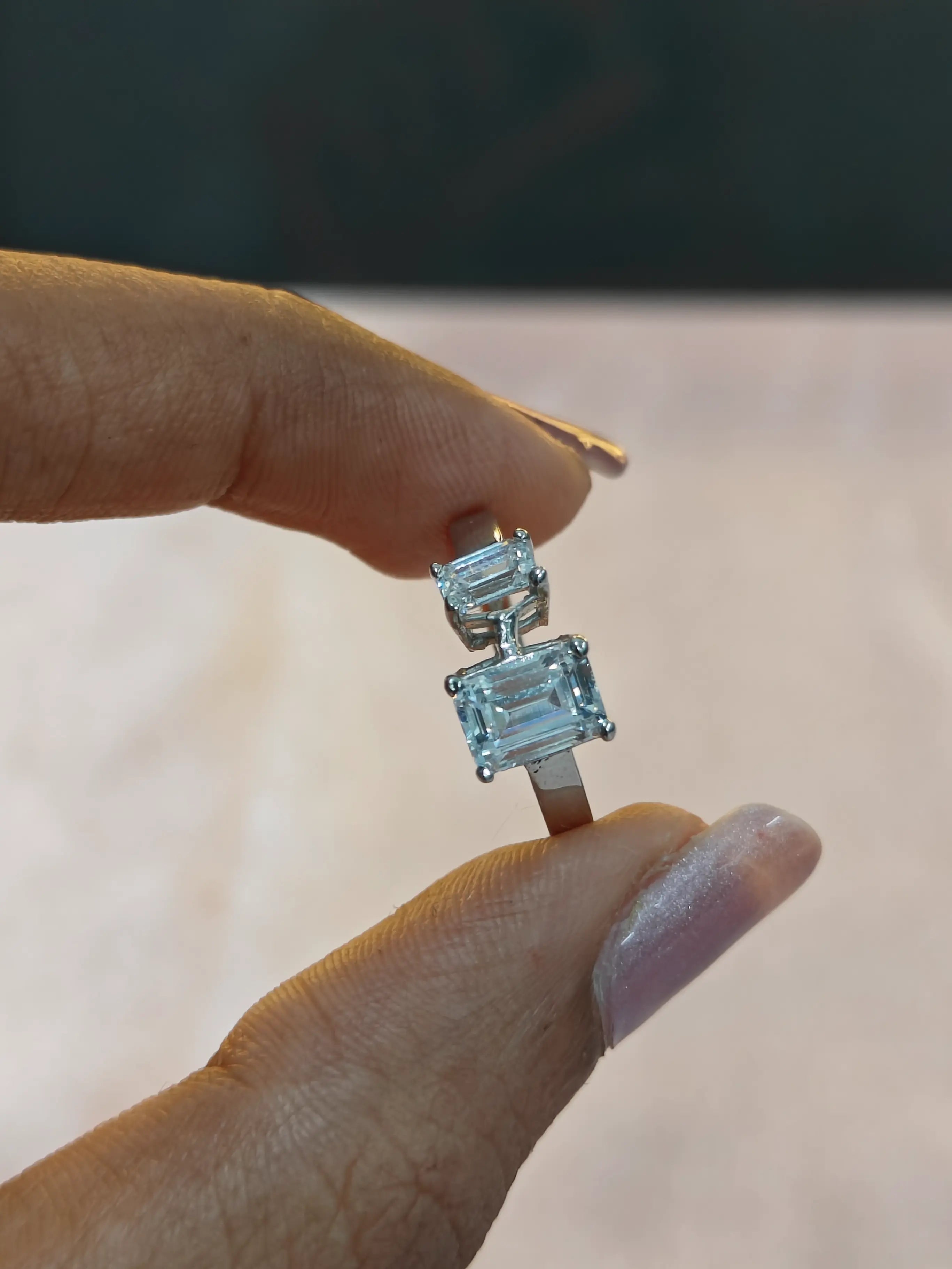 Diamond ring held between fingers with a blurred background