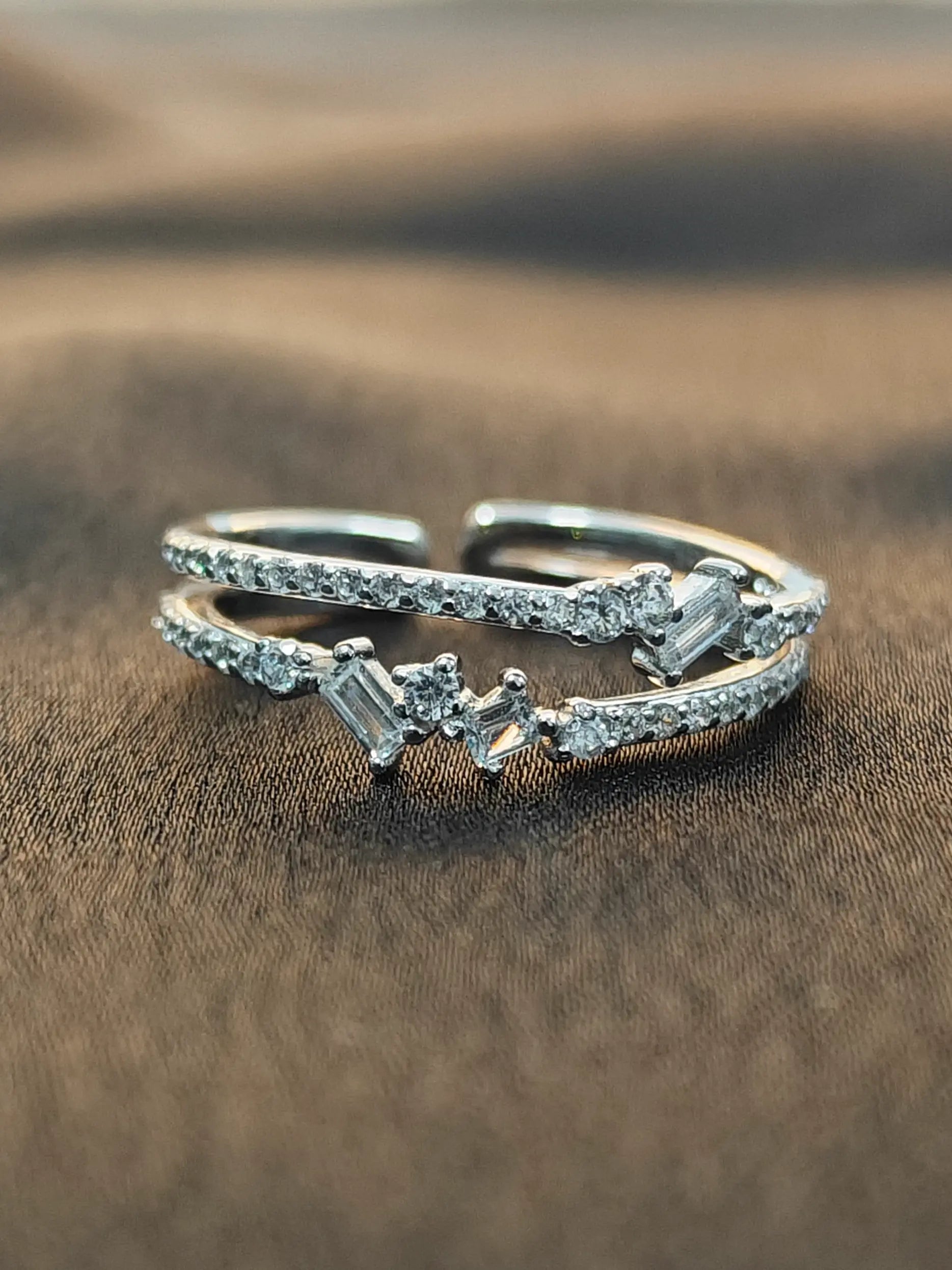 Silver ring with gemstones on a brown fabric background