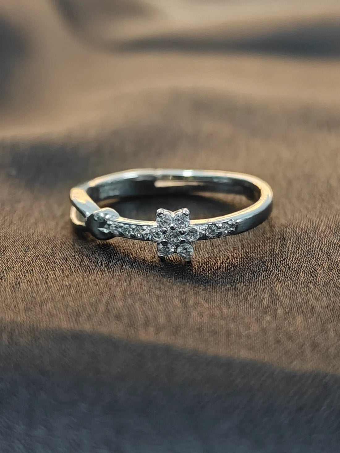 Silver ring with a diamond on a brown fabric background