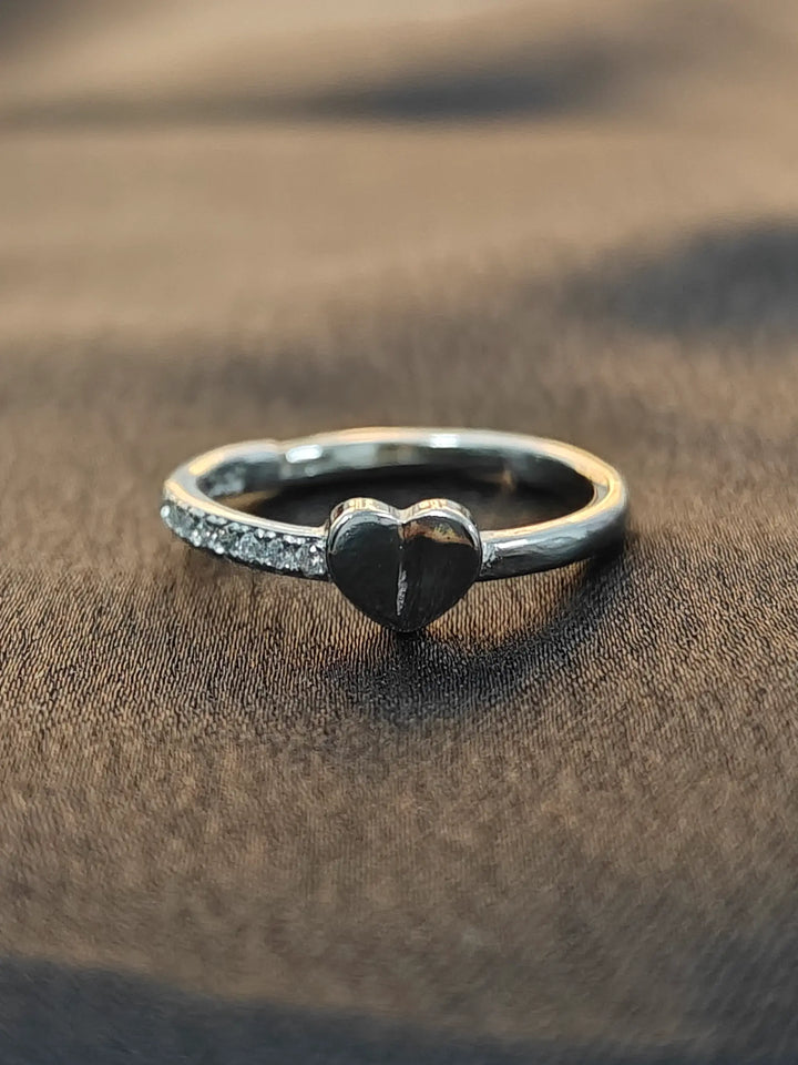 Silver ring with a heart-shaped design on a brown fabric background