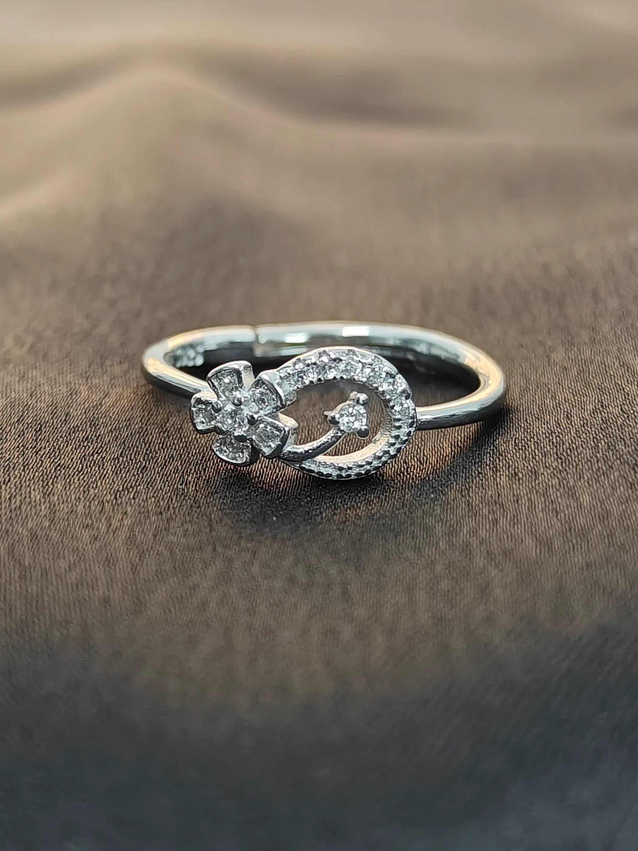 Silver ring with floral design on a textured brown surface