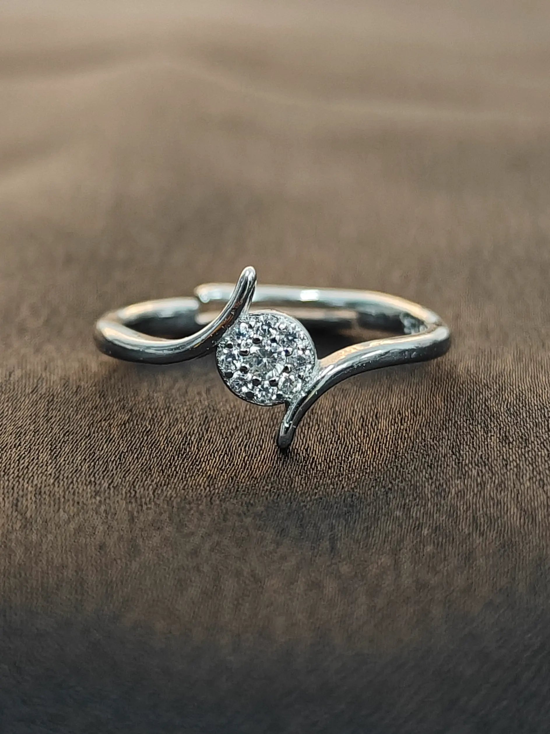 Silver ring with a circular gemstone on a brown fabric background