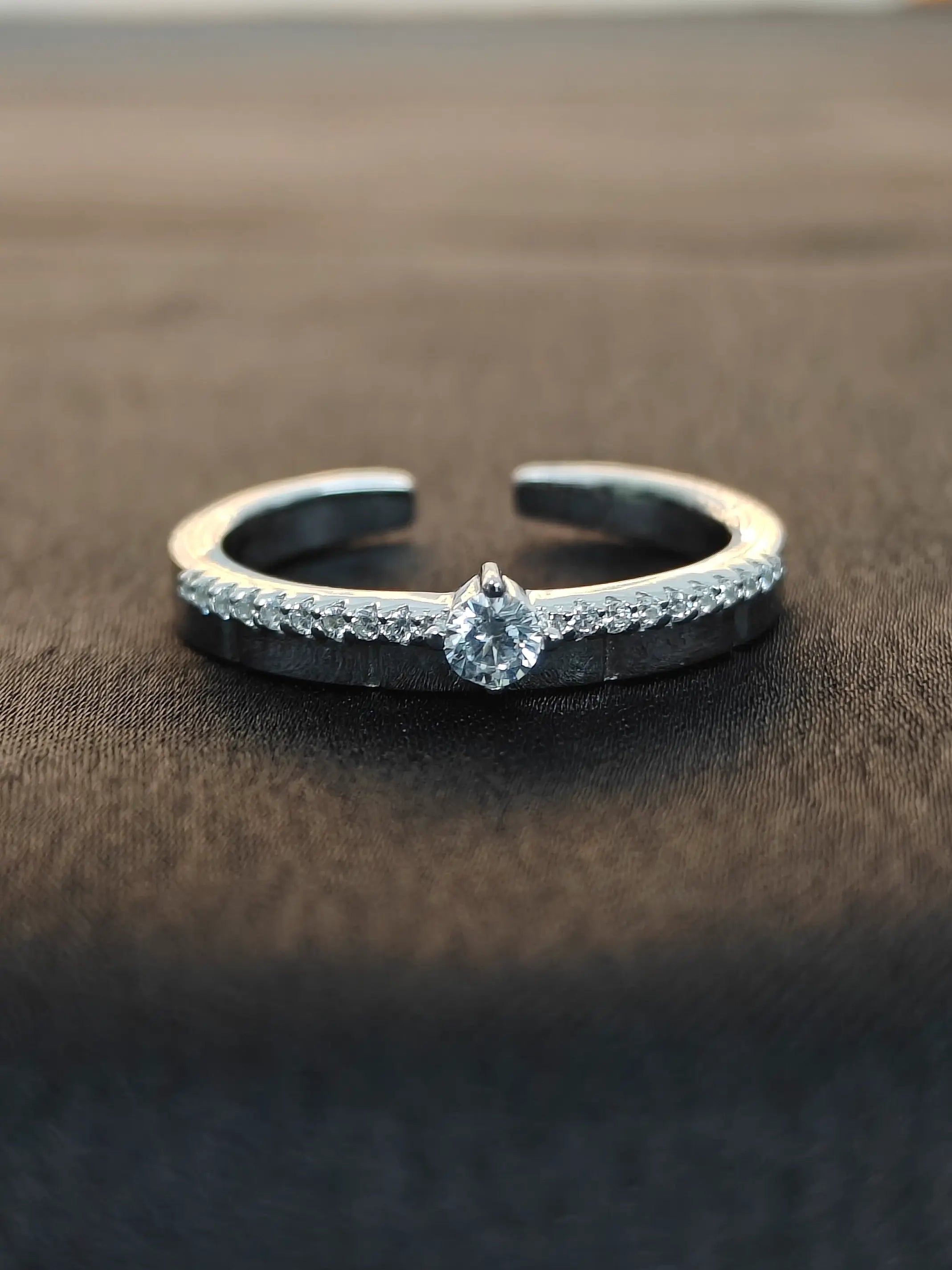 Silver ring with a central diamond on a dark fabric background