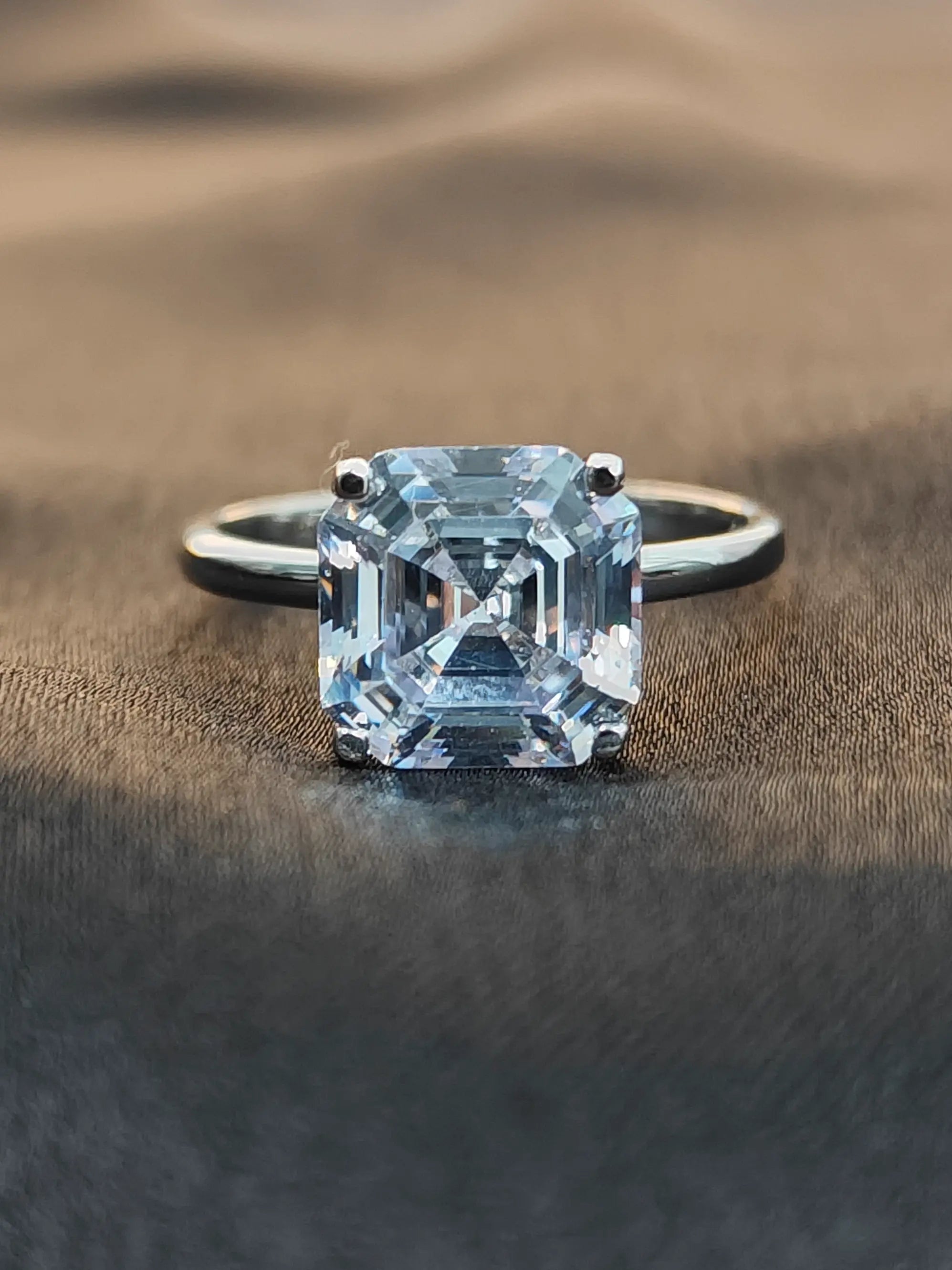 Diamond ring with a light blue gemstone on a textured brown surface