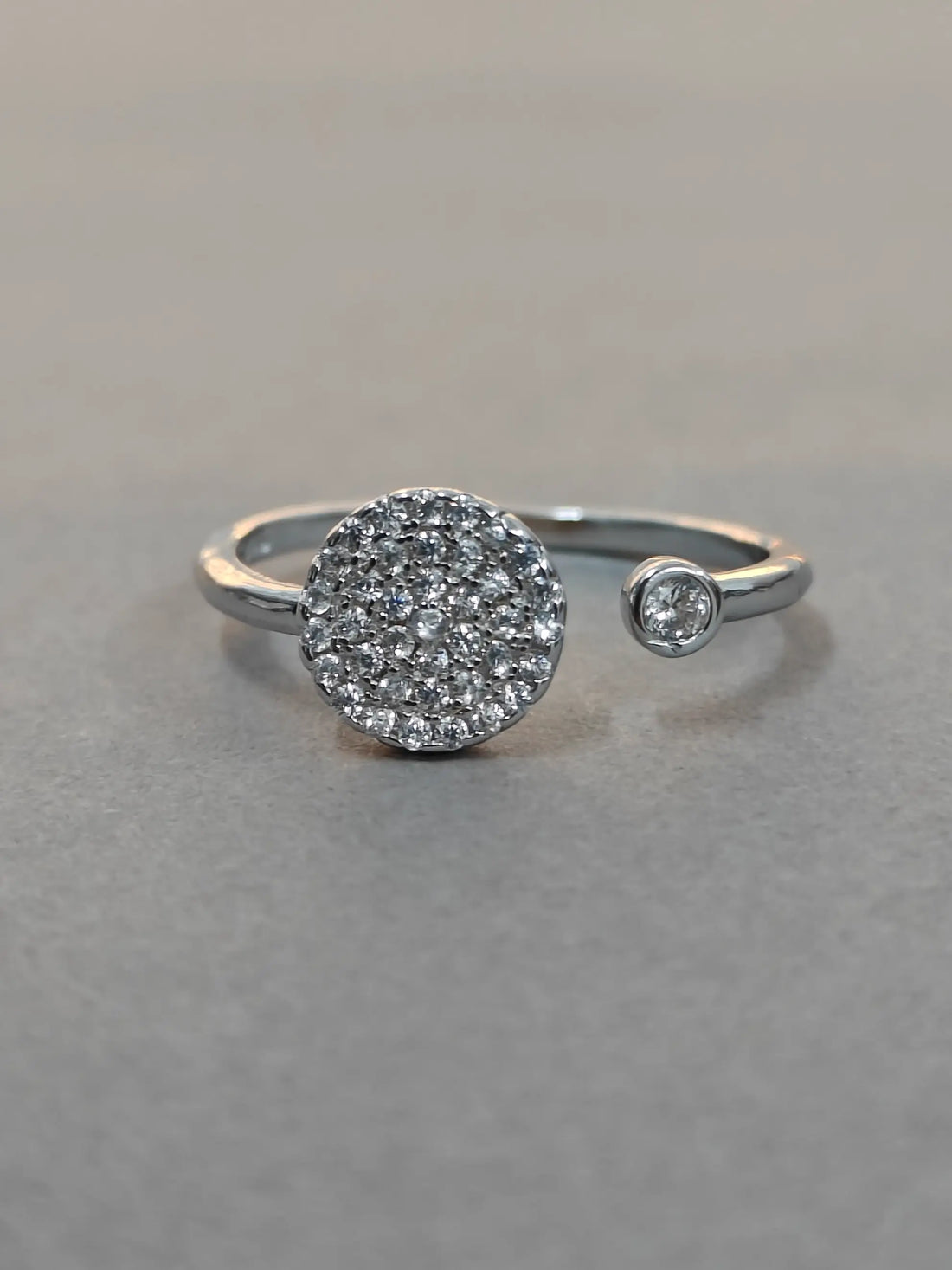 Silver ring with diamond accents on a gray background