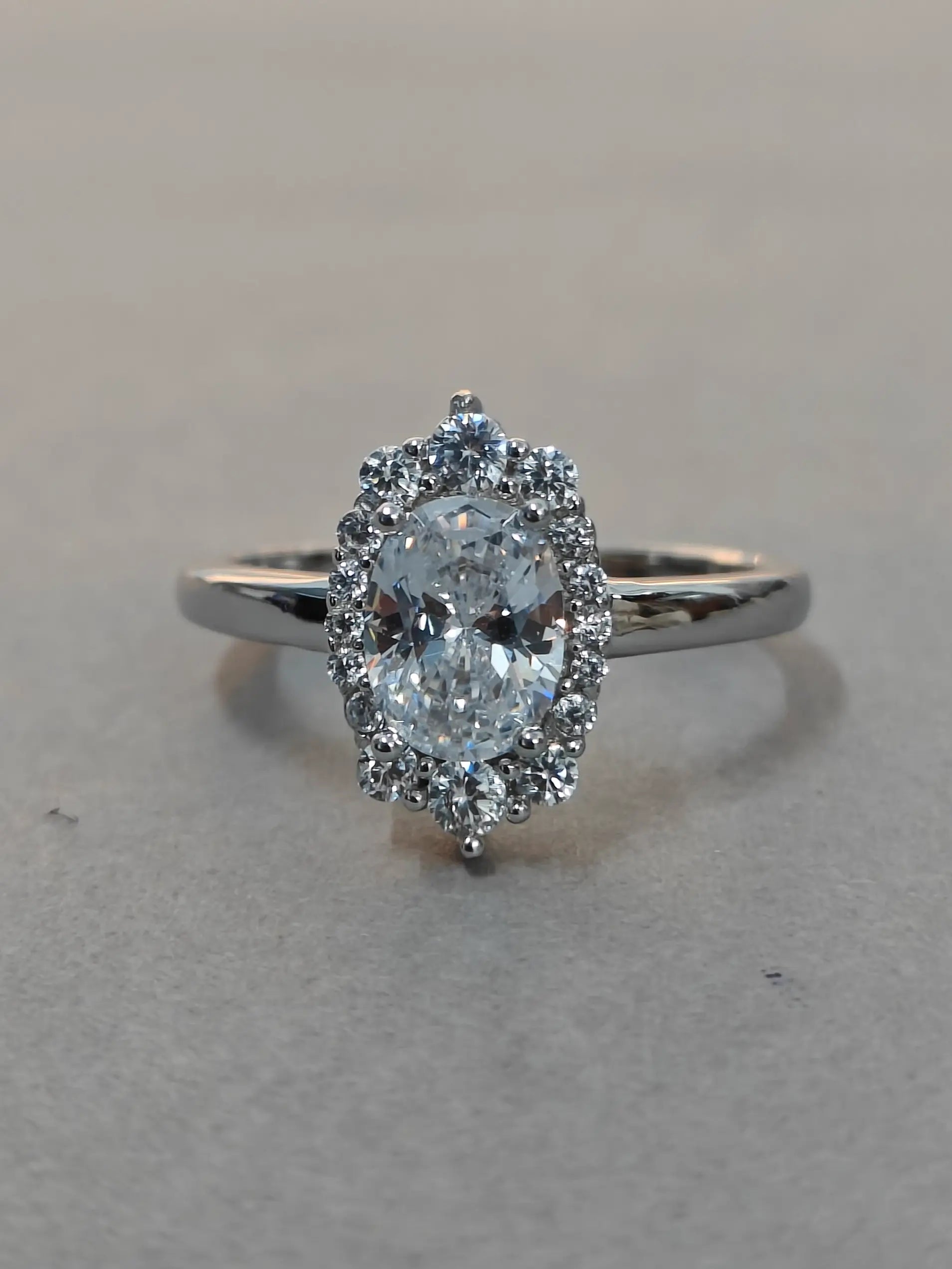 Diamond ring with a central gemstone and smaller diamonds on a gray background