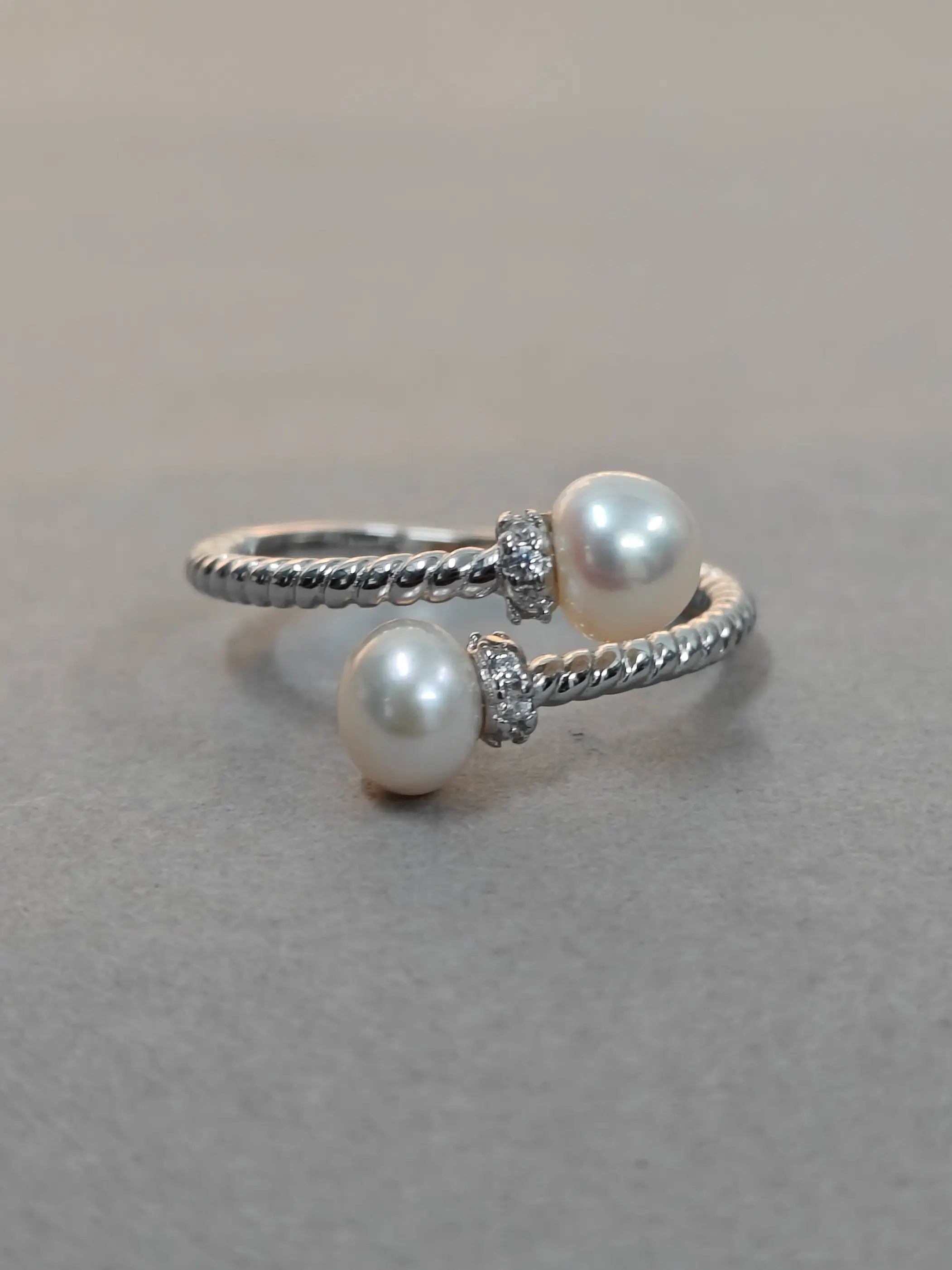 Silver ring with two pearls on a gray background
