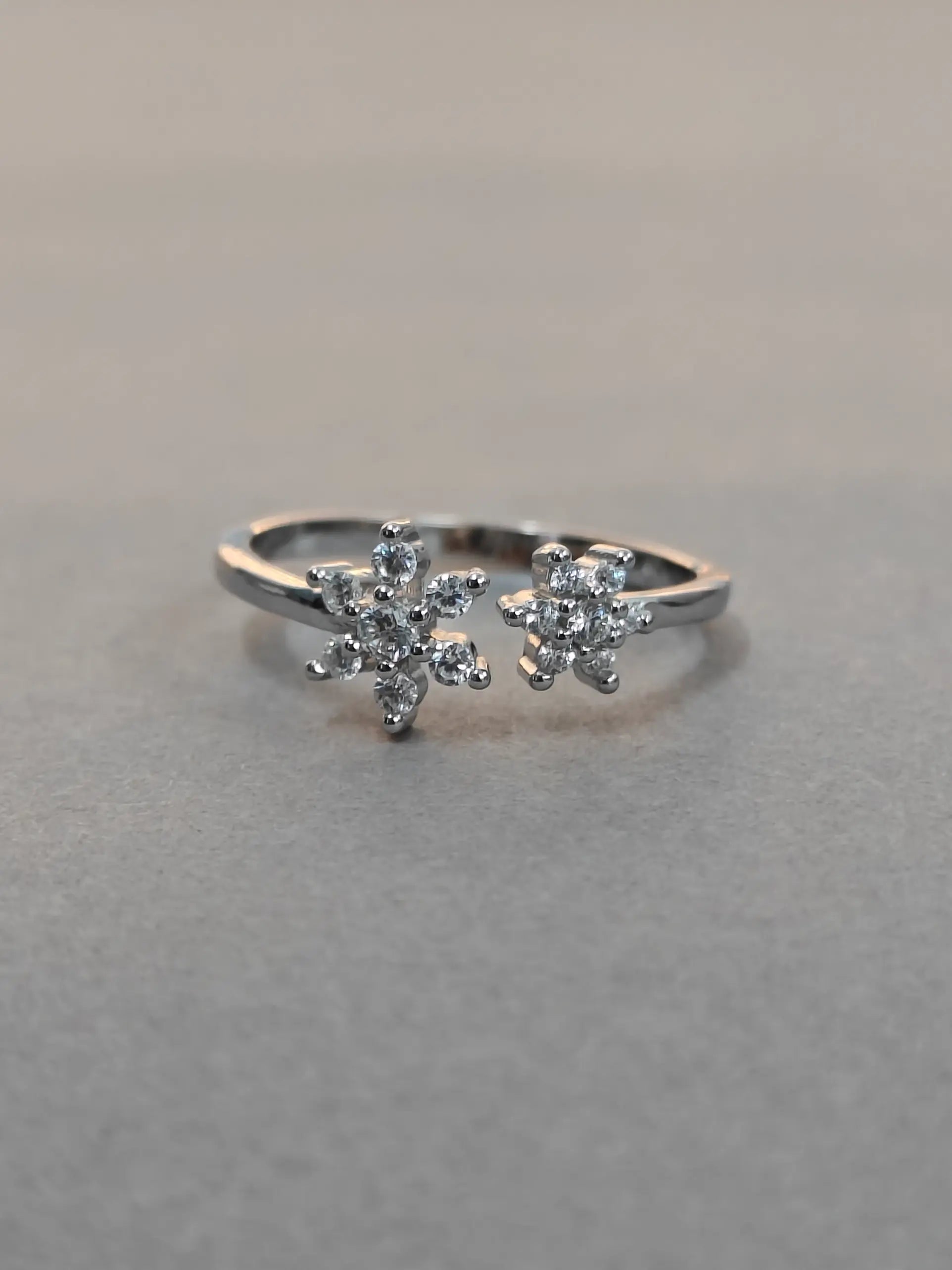 Silver ring with floral design on a gray background