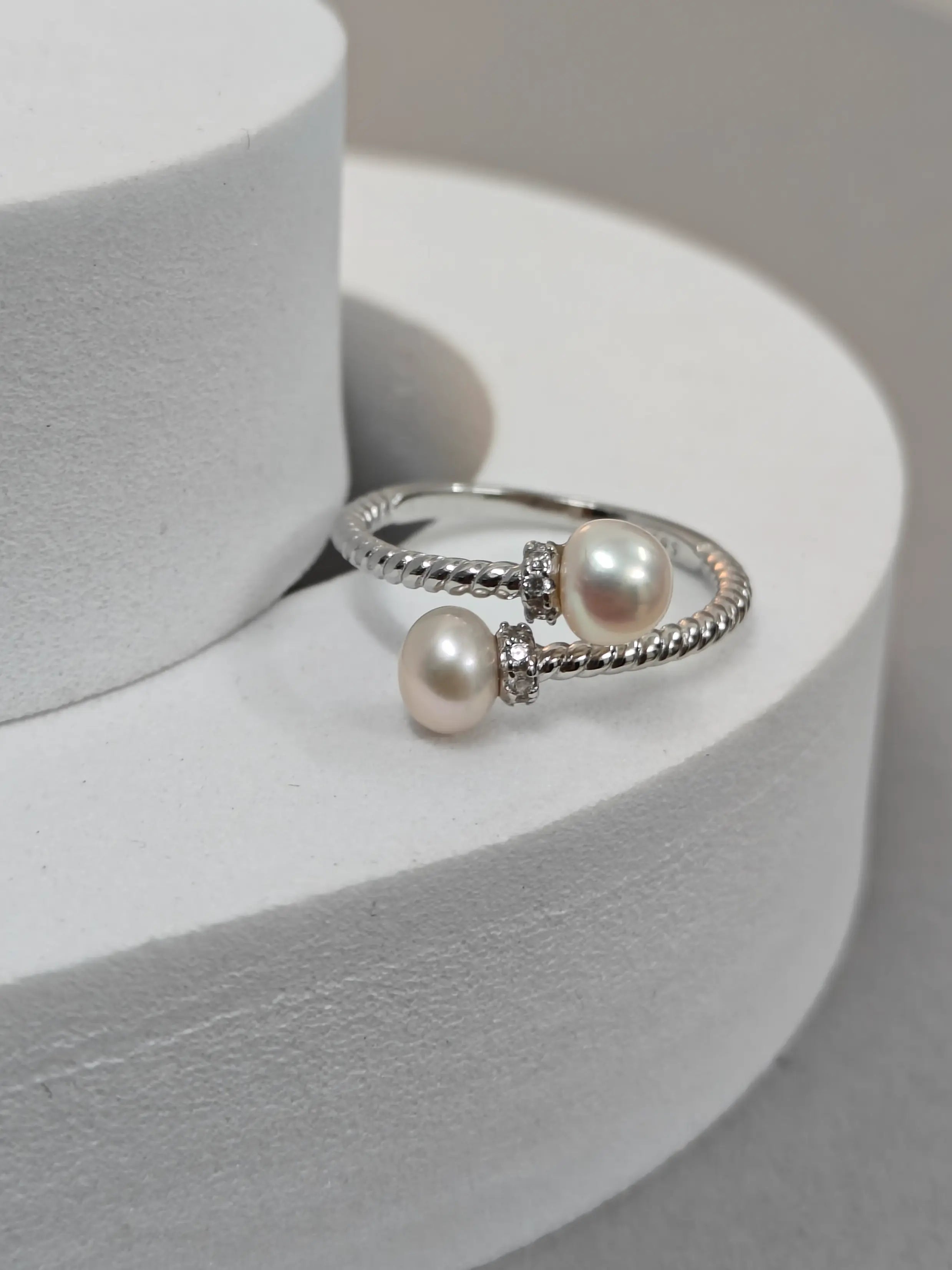 Silver ring with two pearls on a white stand