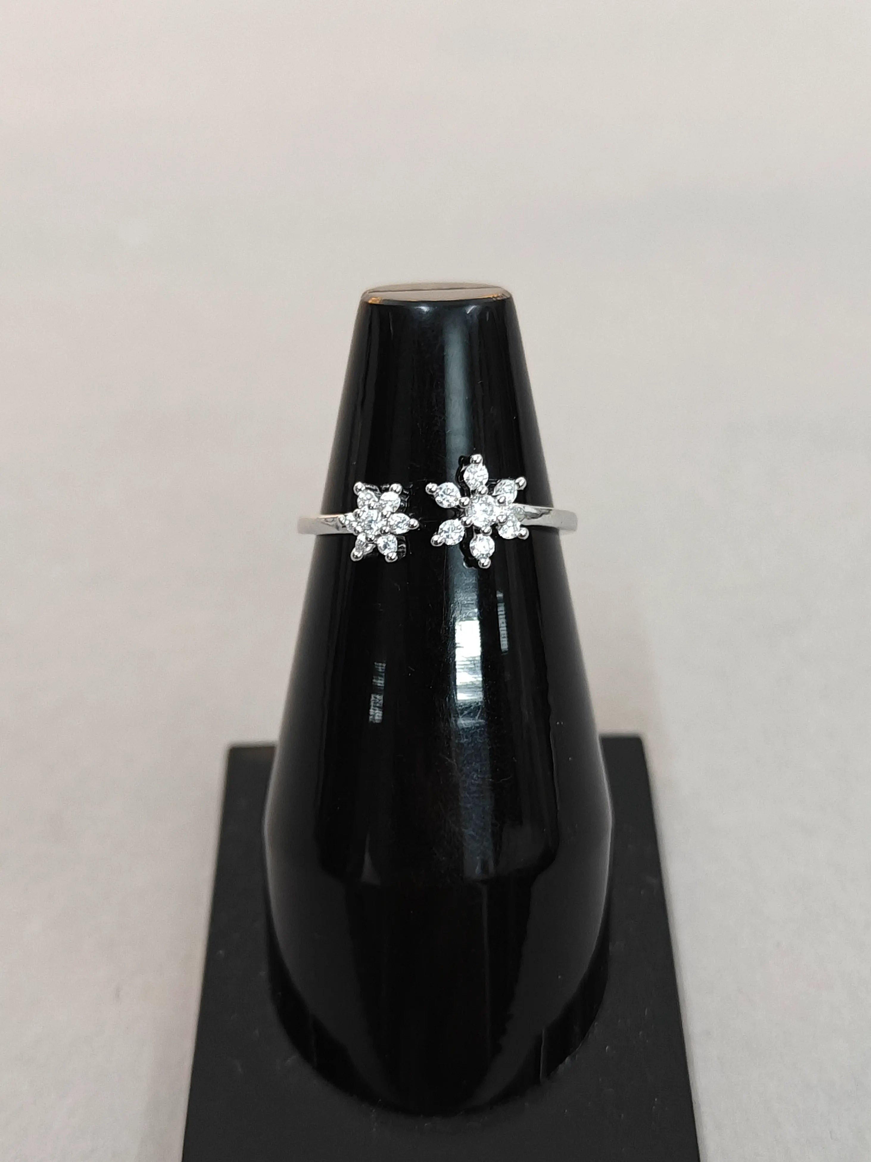 Pair of silver earrings on a black stand against a light gray background