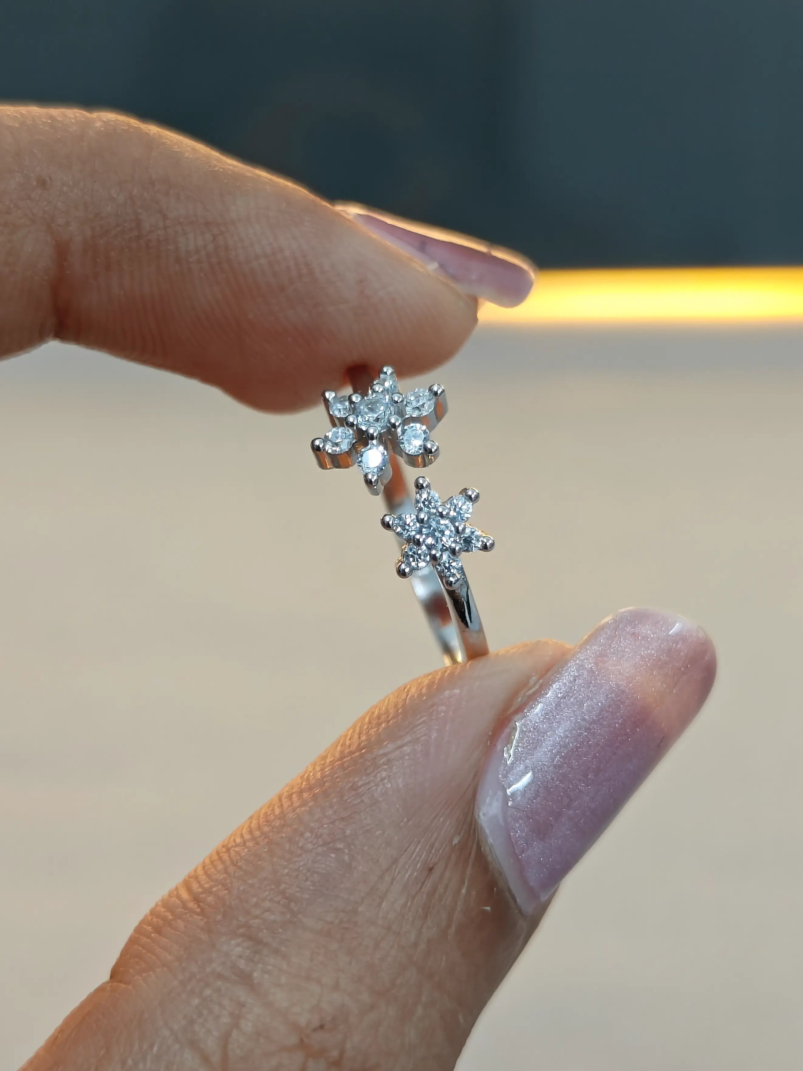Diamond ring held between fingers with a blurred background