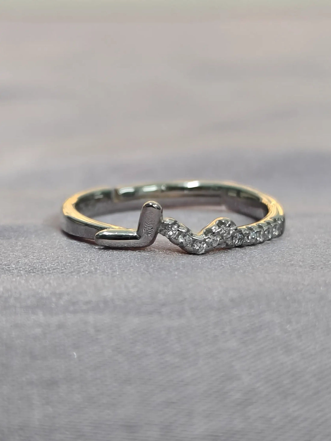 Silver ring with a small diamond on a gray background