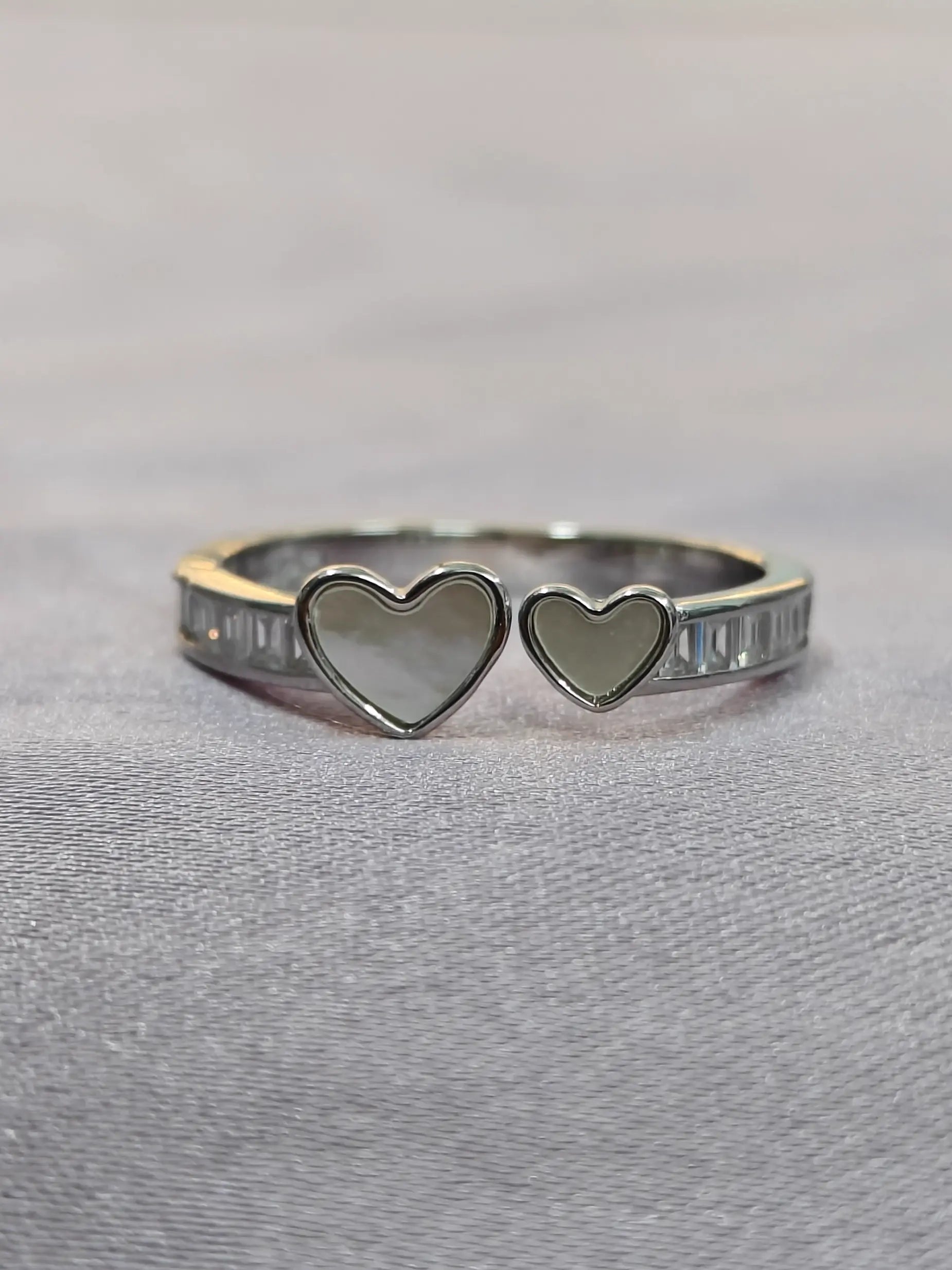 Silver ring with heart-shaped stones on a gray background