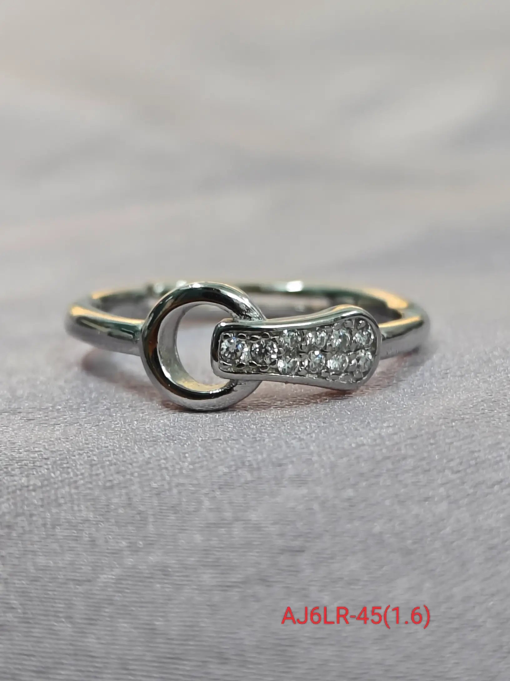 Silver ring with diamond accents on a light gray background