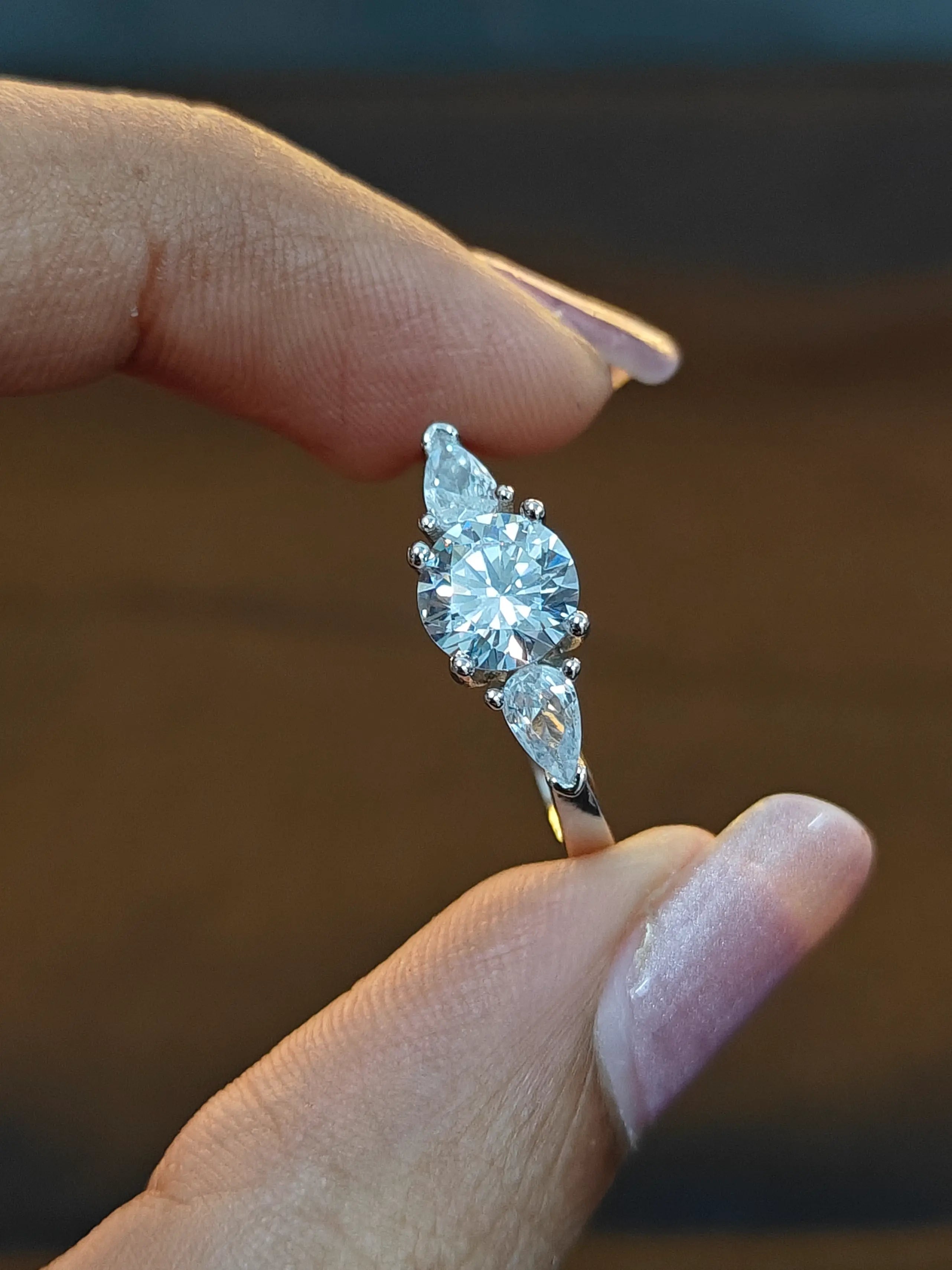 Diamond ring held between fingers against a blurred background