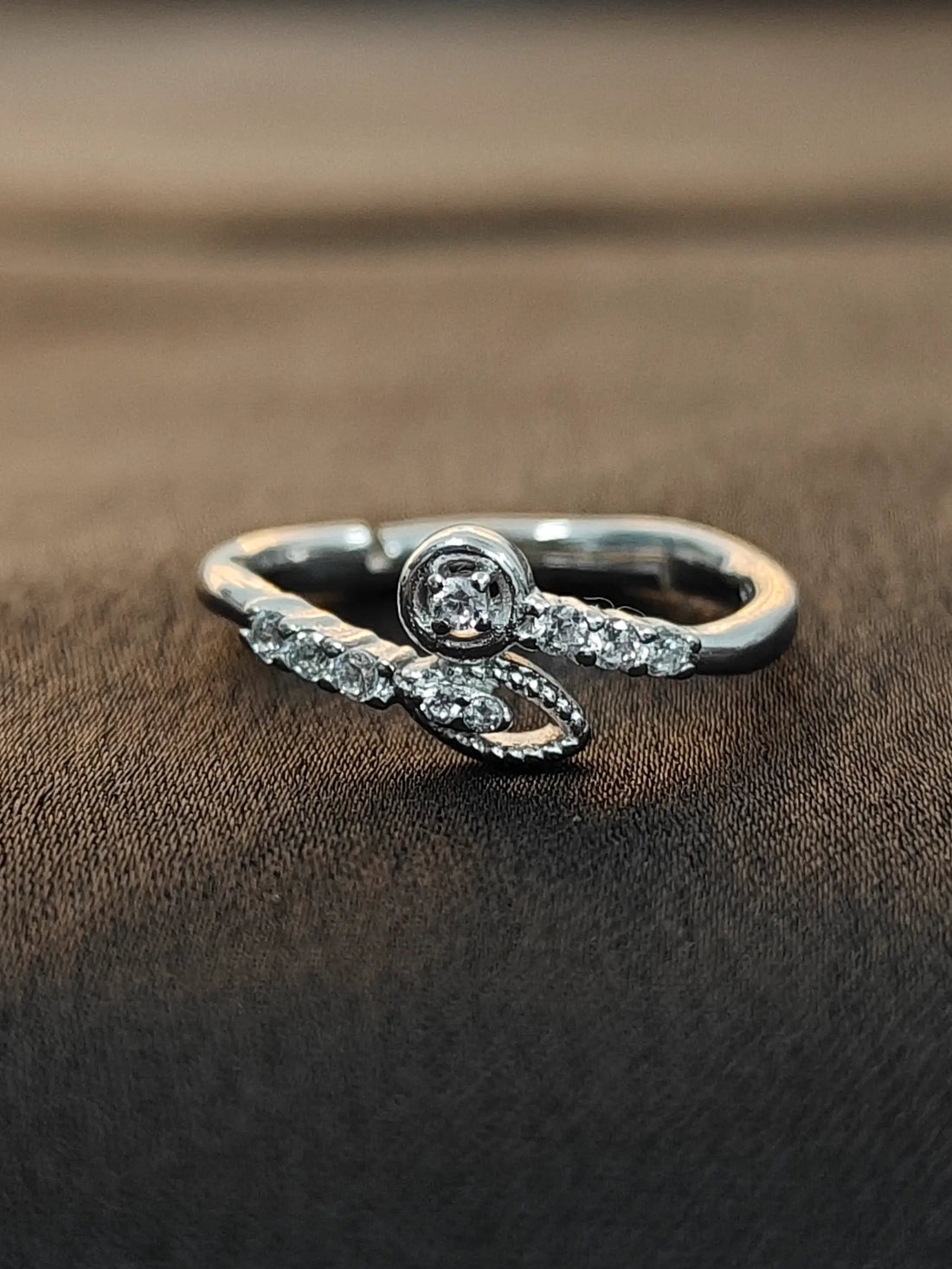 Silver ring with a diamond on a brown fabric background