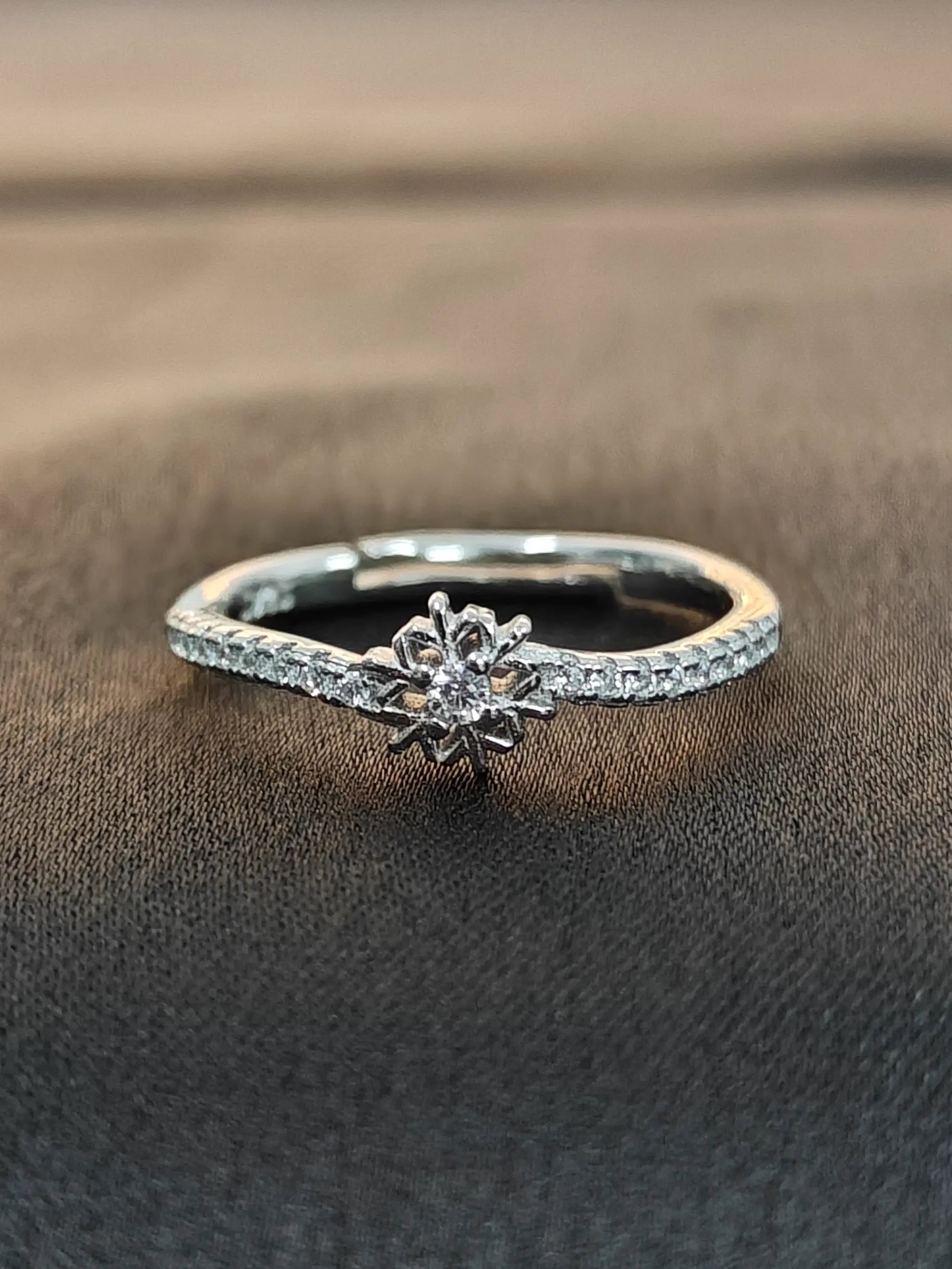 Silver ring with a diamond on a brown fabric background