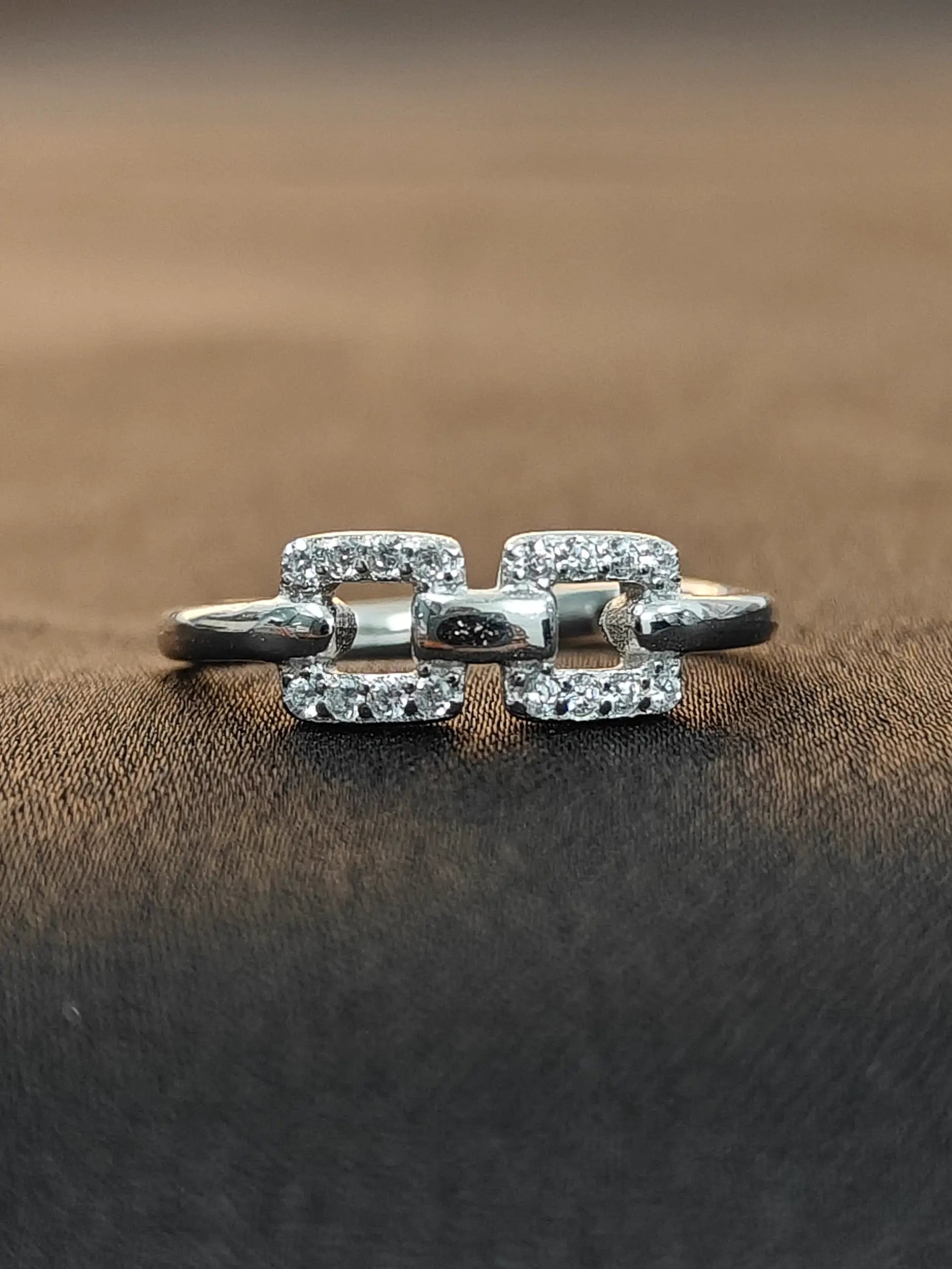 Silver ring with diamond accents on a brown fabric background