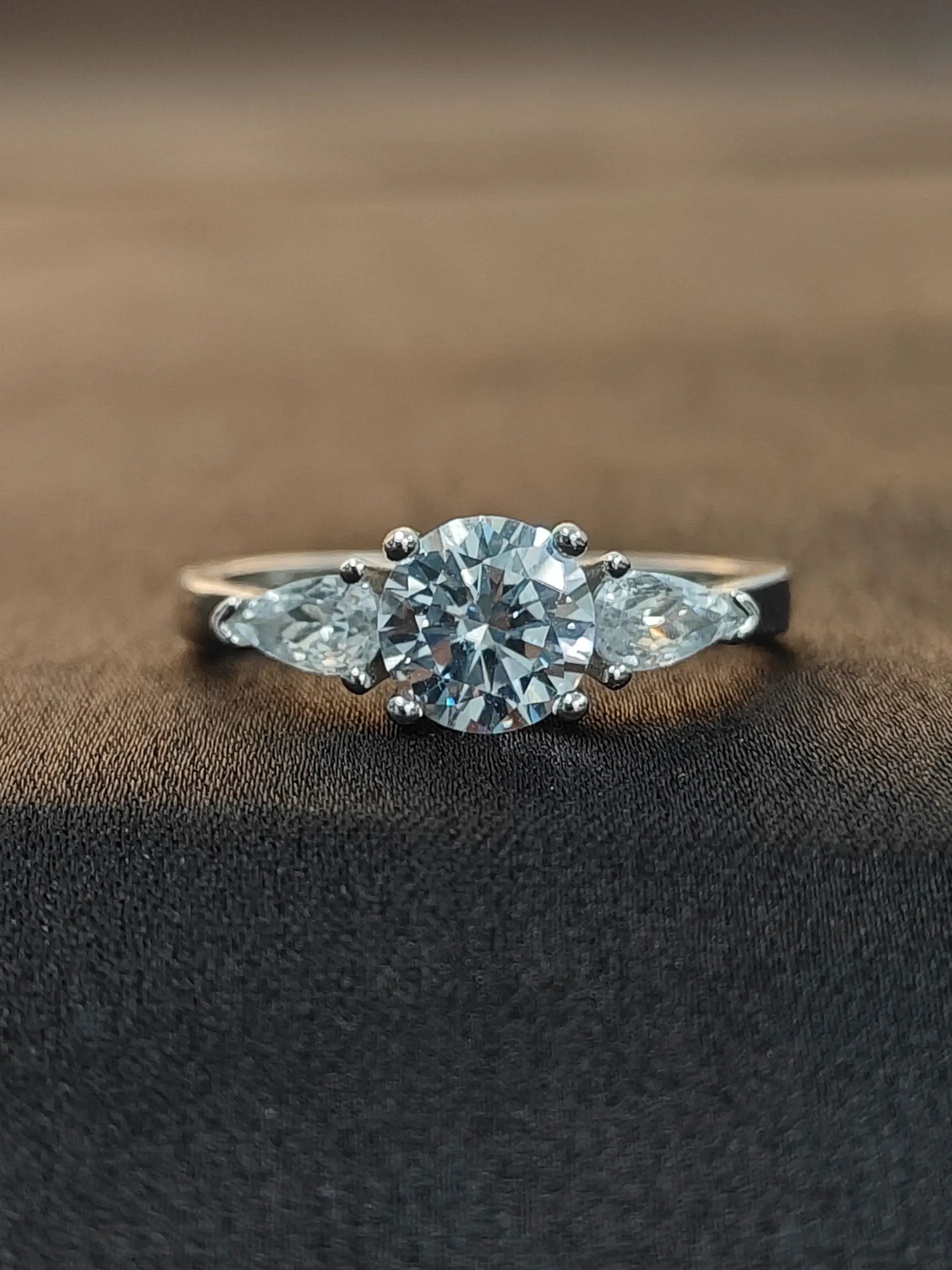 Diamond ring with three stones on a brown fabric background