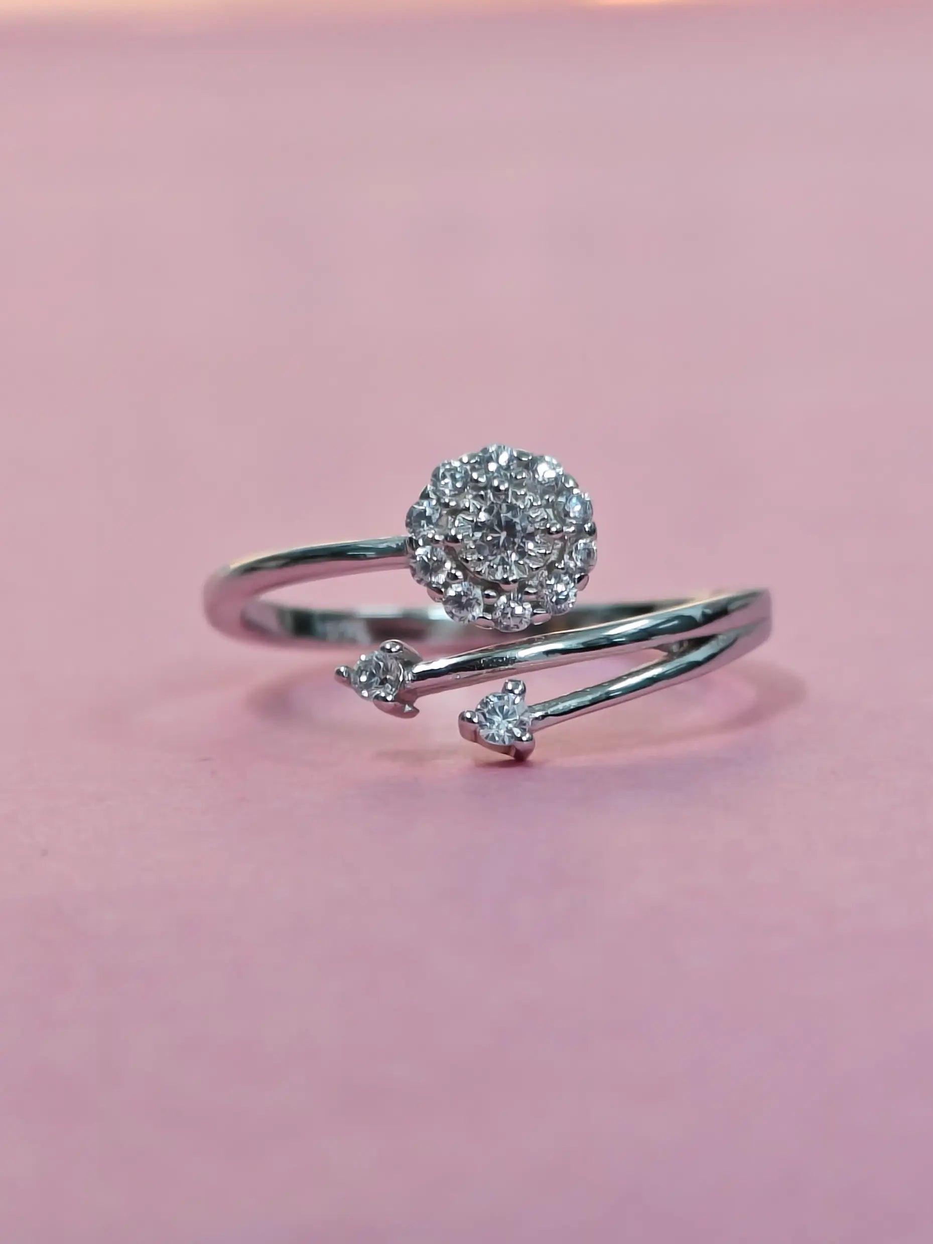 Silver ring with diamond accents on a pink background