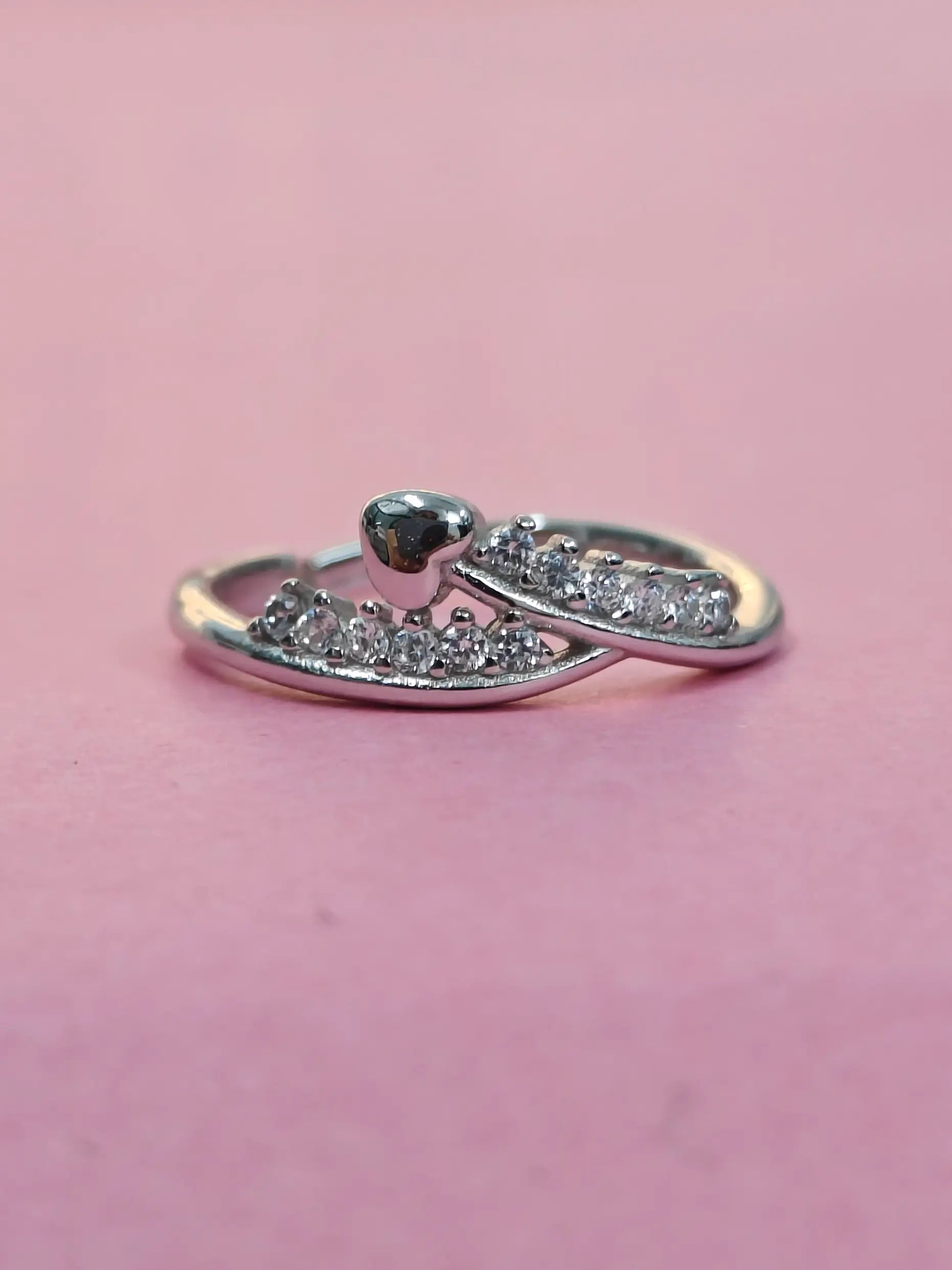 Silver ring with small diamonds on a pink background