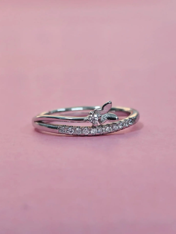 Silver ring with small diamonds on a pink background