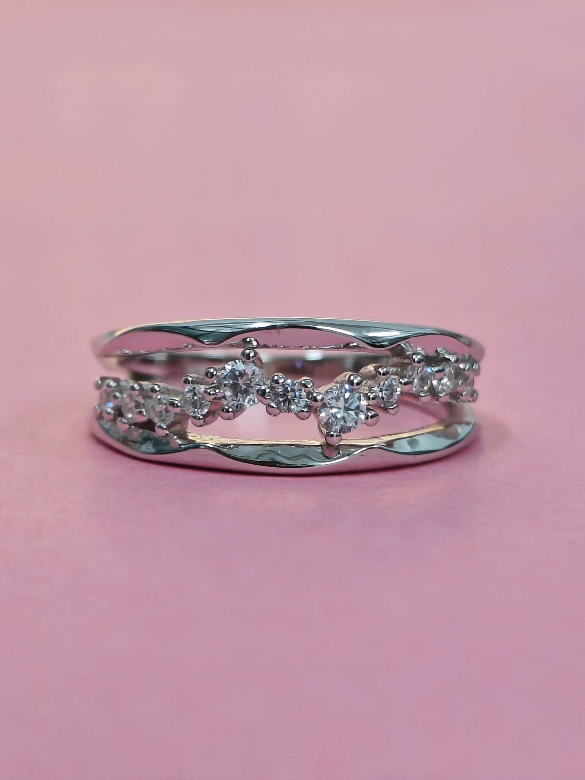 Silver ring with diamonds on a pink background
