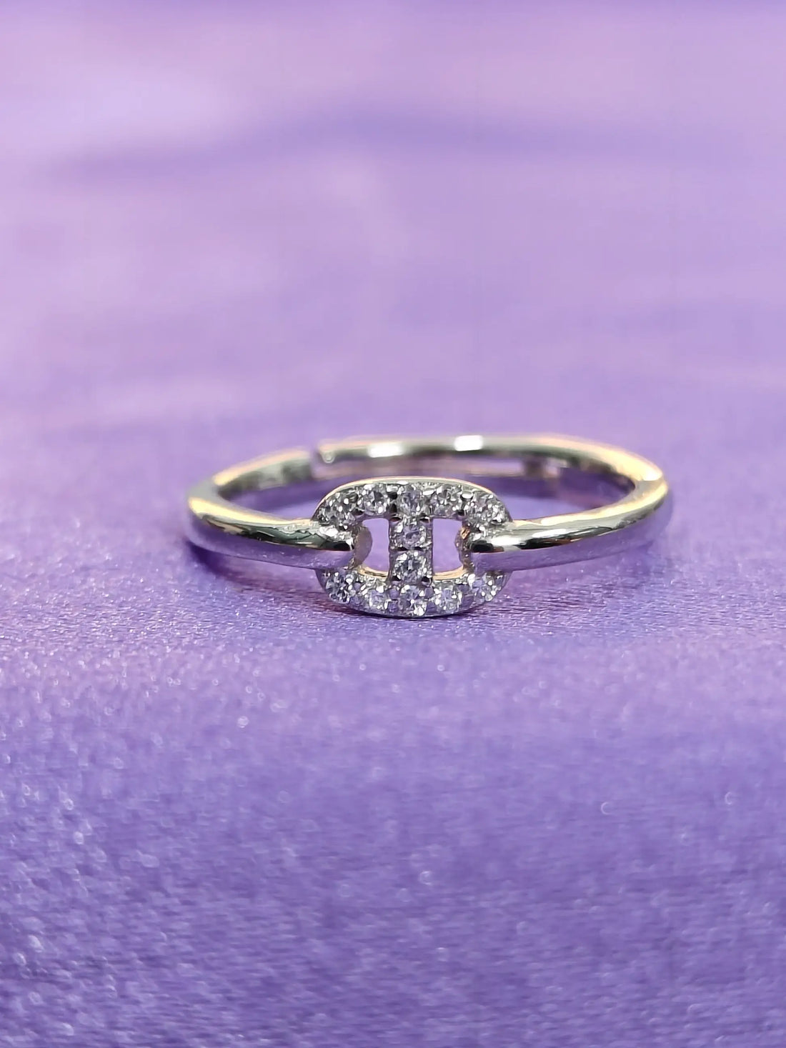 Silver ring with a diamond on a purple fabric background