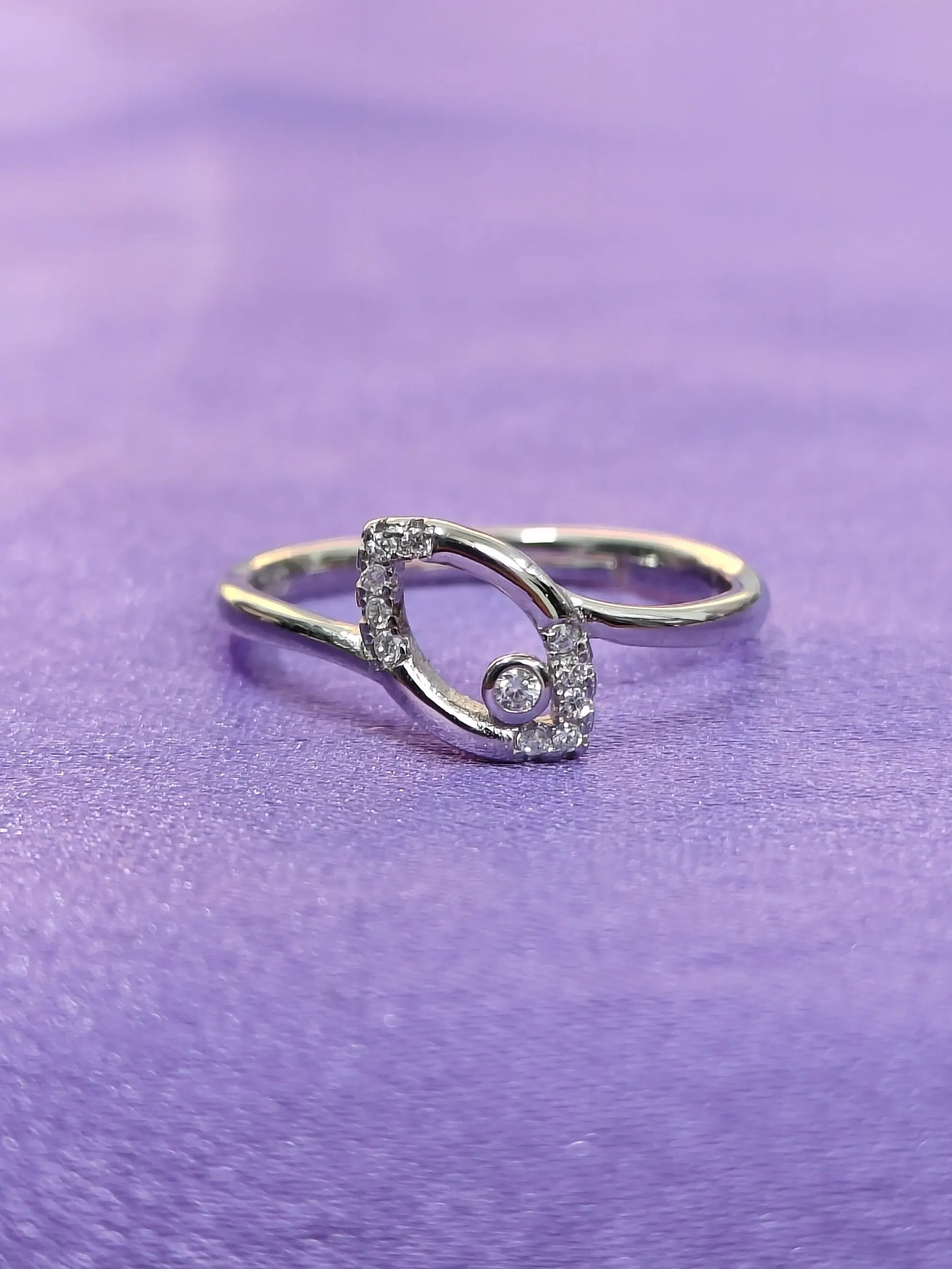 Silver ring with a diamond on a purple fabric background