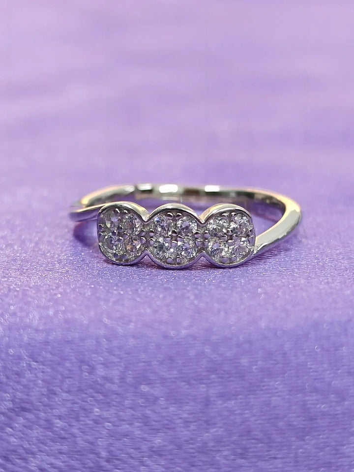 Silver ring with three circular gemstones on a purple background